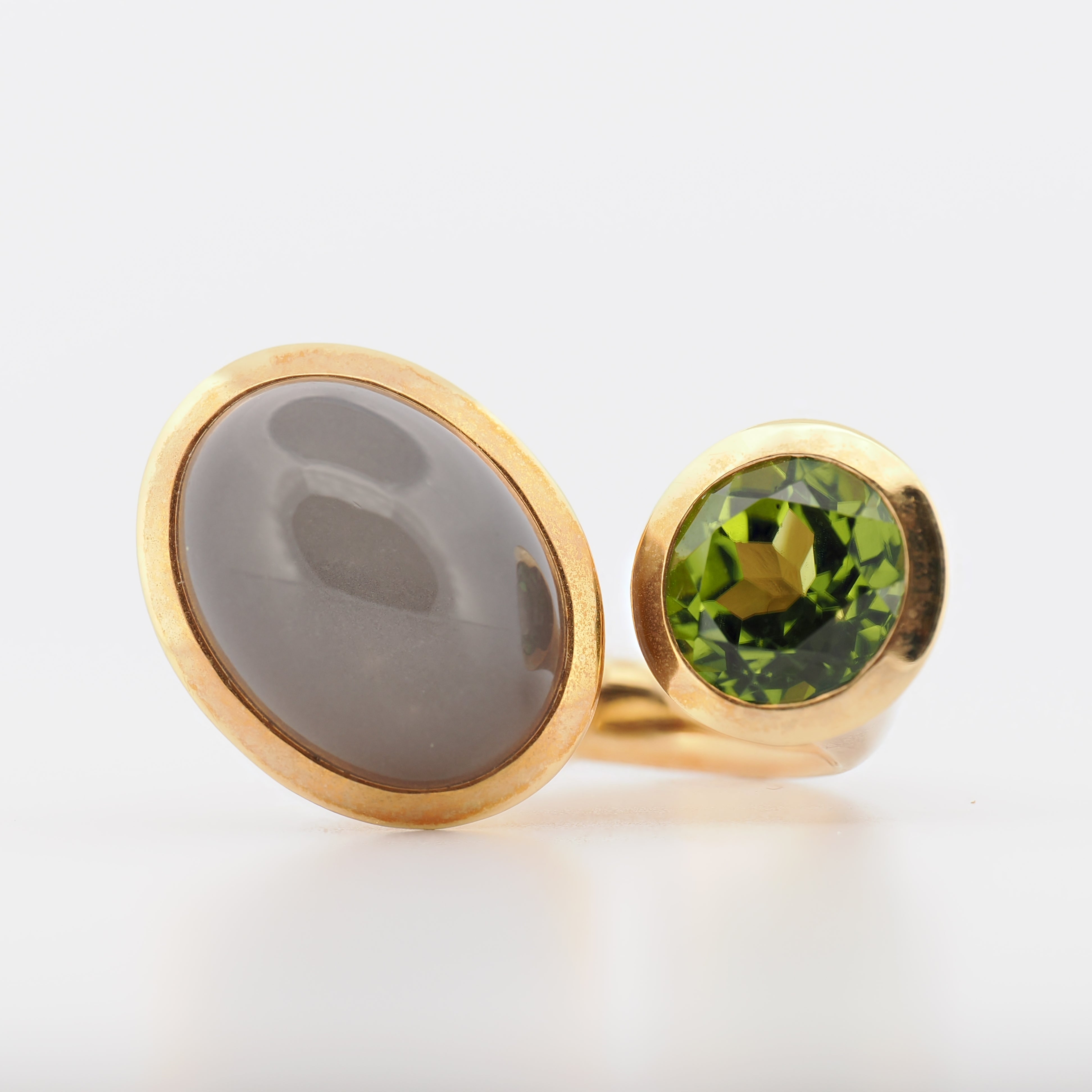 Schneider Schmuckdesign Ring in 18K Gelbgold mit Mondstein und Turmalin vor hellem Hintergrund