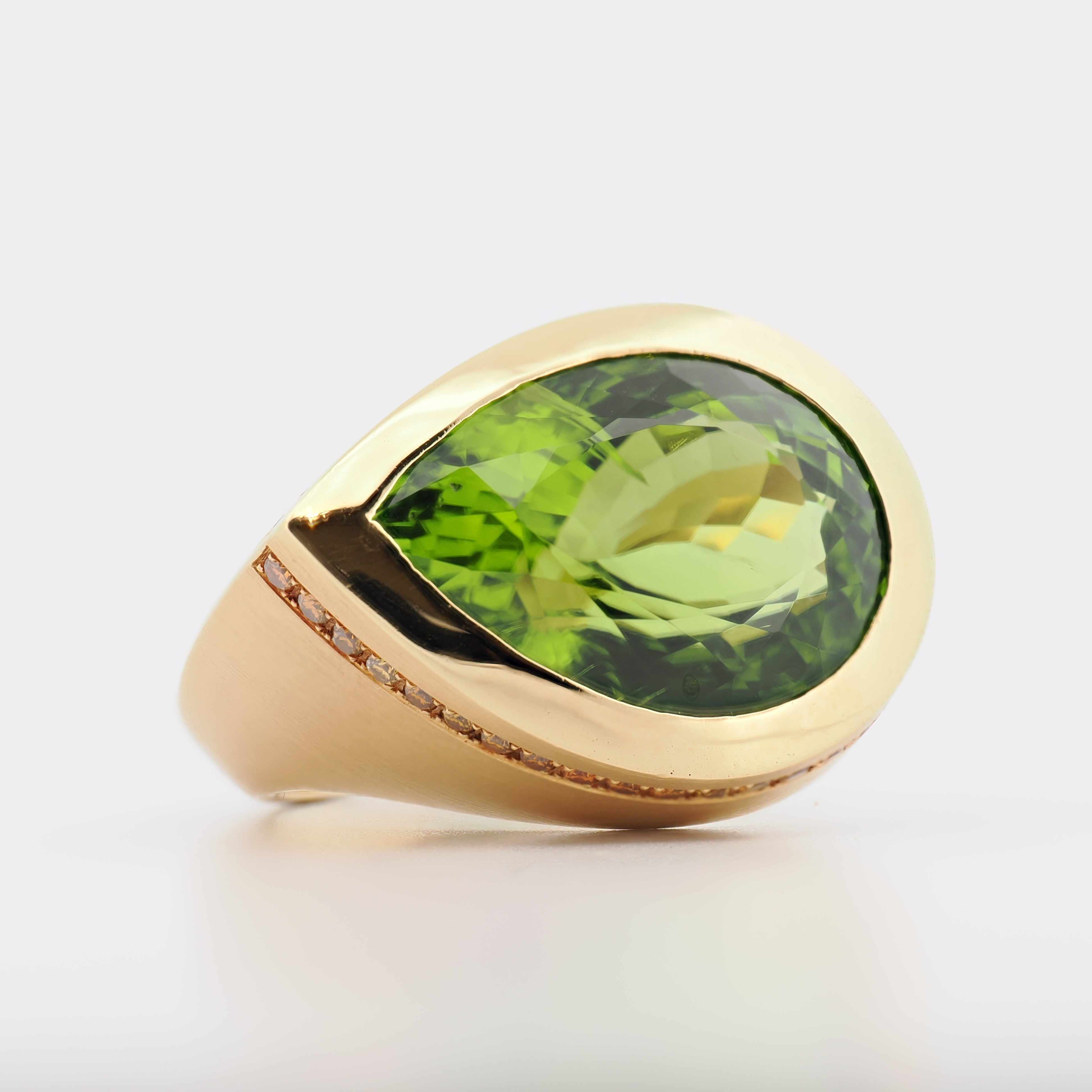 Schneider Schmuckdesign Ring aus 18k Gelbgold mit marquiseschliff Peridot und kleinen Diamantenbesatz auf hellem Hintergrund