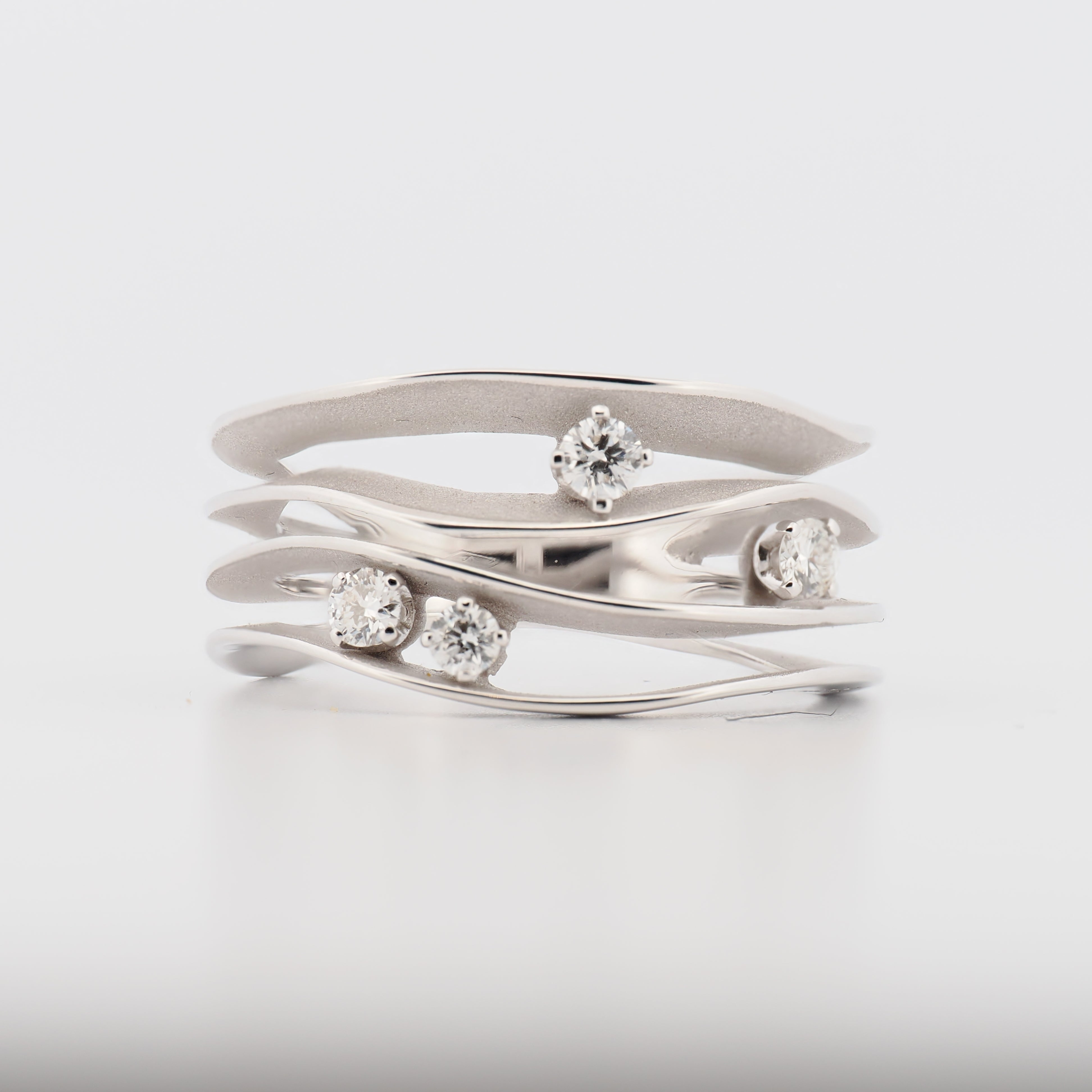 Annamaria Camilli Dune Ring aus 18k Weißgold mit 4 Diamanten vor neutralem Hintergrund