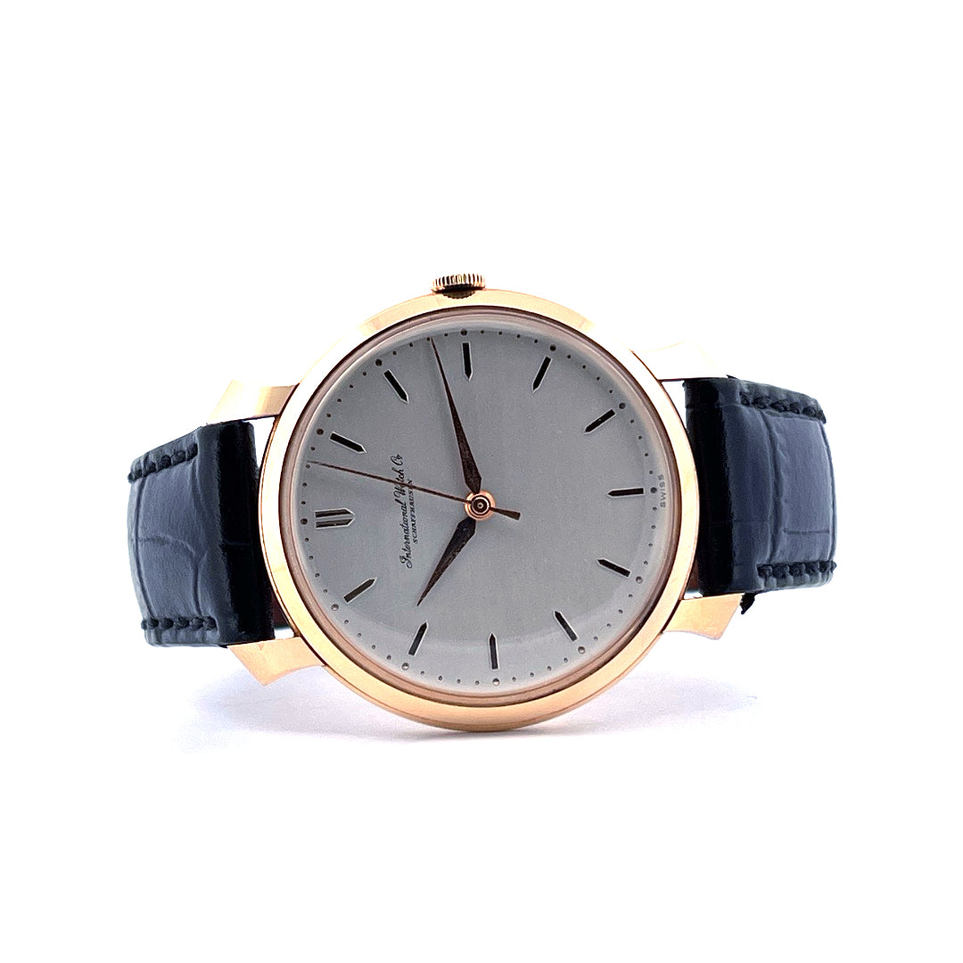 IWC Shark Fin Uhr mit grauem Zifferblatt und schwarzem Lederarmband, goldfarbenes Gehäuse, Frontansicht auf weissem Hintergrund