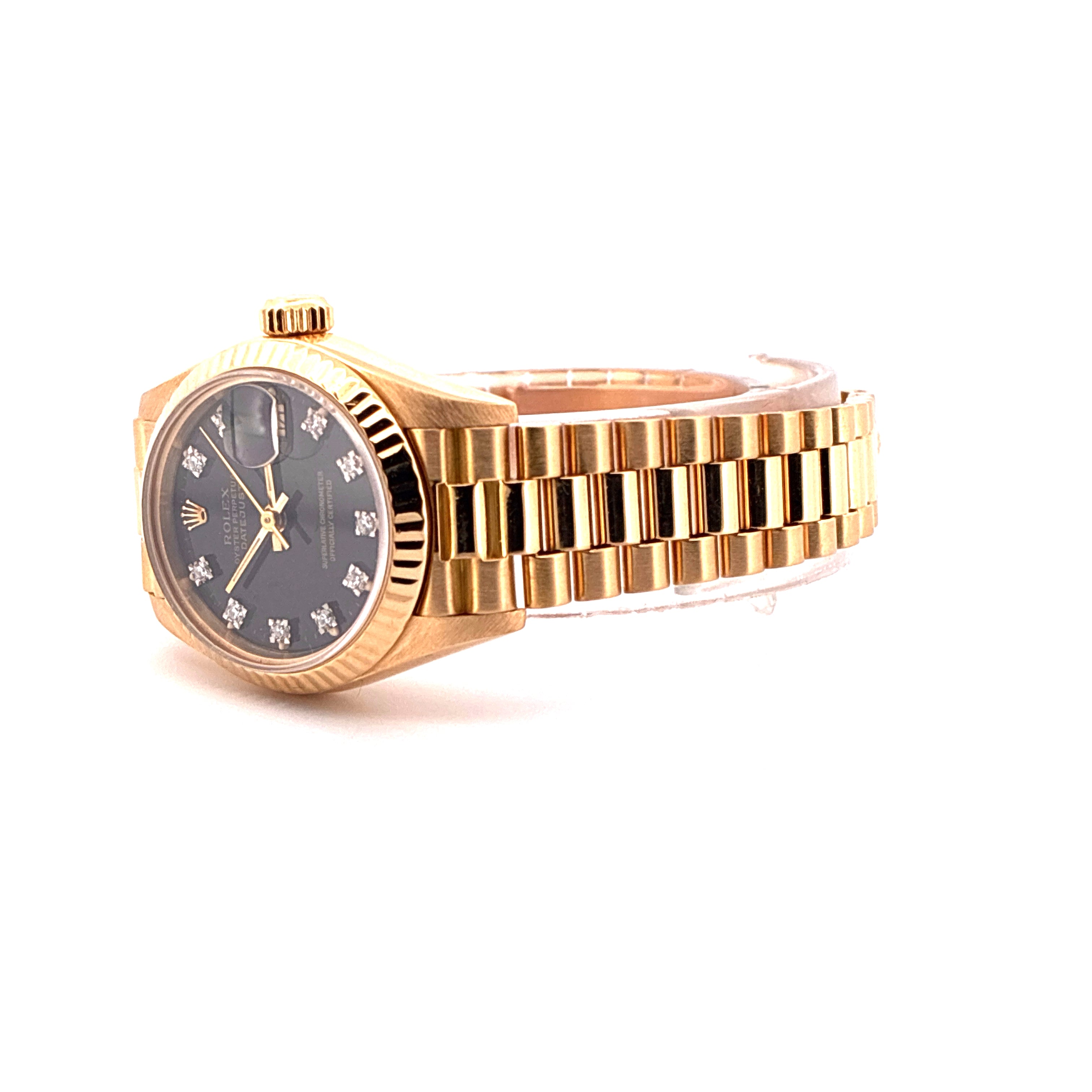 Eine goldene Rolex Lady-Datejust mit schwarzem Zifferblatt und 10 Diamant-Indizes, von der Seite fotografiert, auf weissem Hintergrund