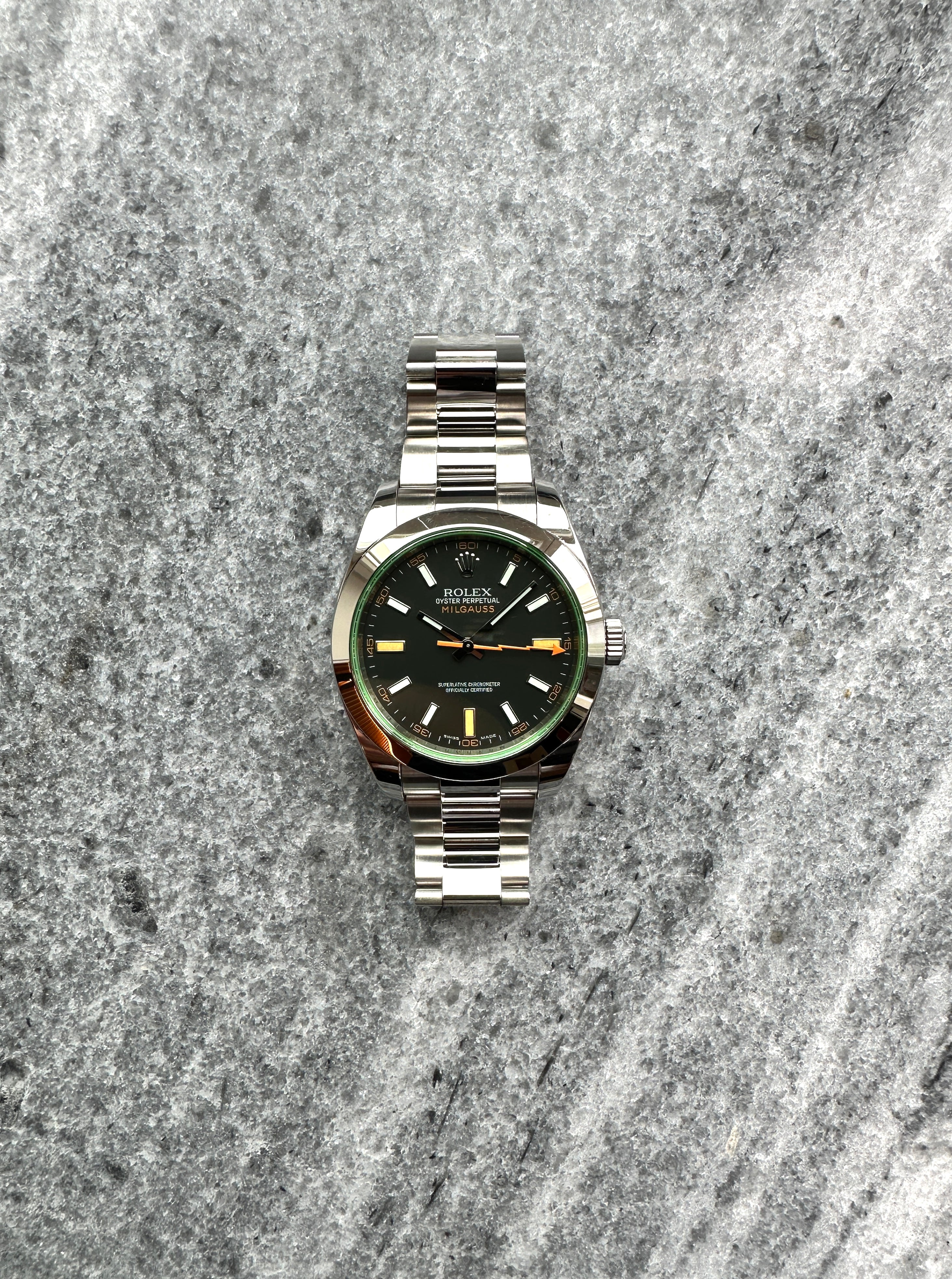 Rolex Milgauss 116400GV in Stahl Frontansicht auf grauem Steinboden mit einem dunkelgrünen Zifferblatt