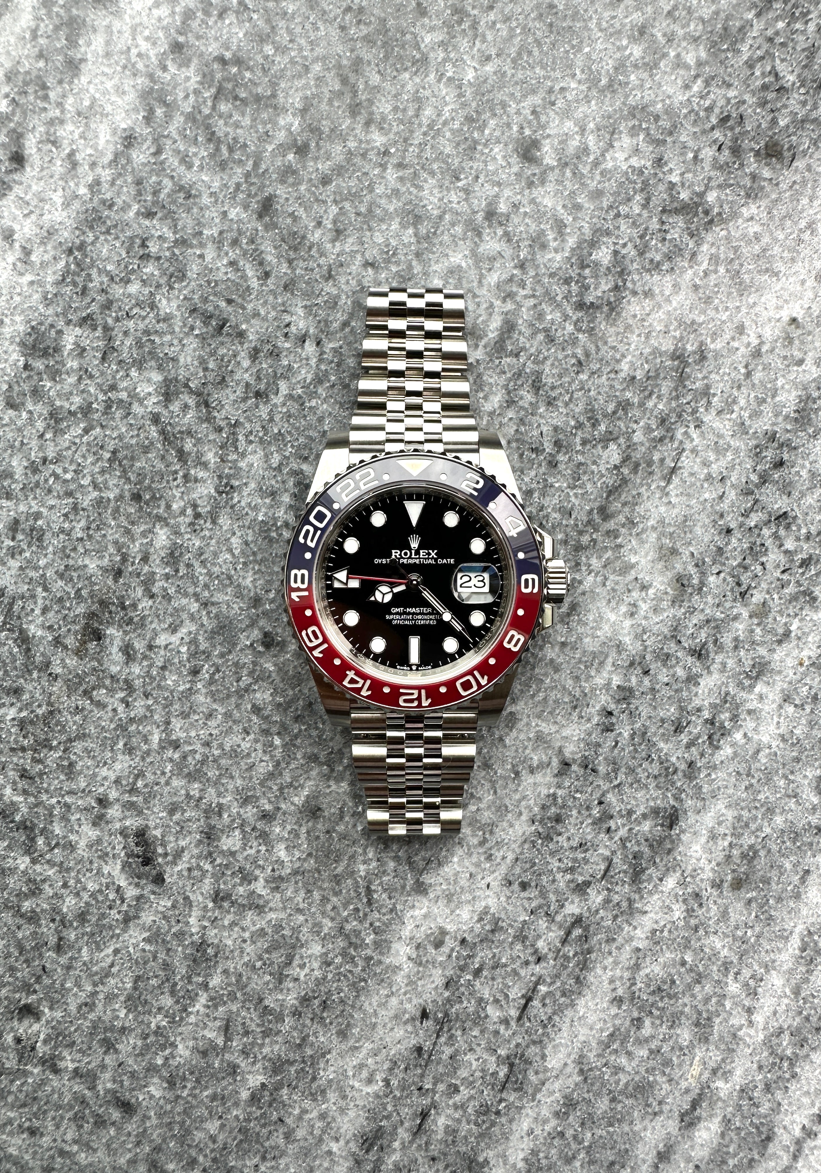 Rolex GMT-Master II Pepsi, Edelstahl, Frontansicht, auf grauem Untergrund
