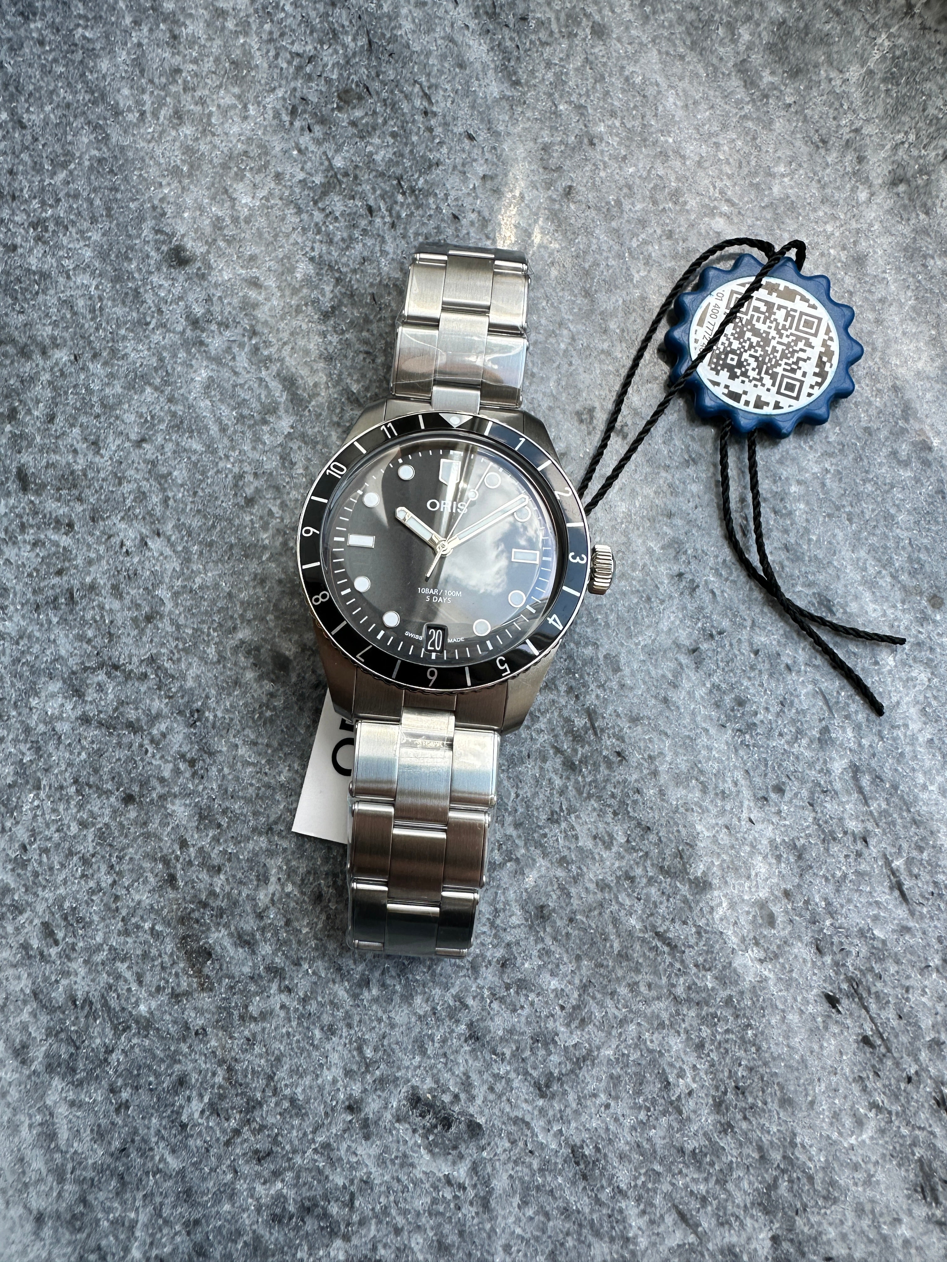 Oris Divers Sixty-five 12h Calibre 400, Edelstahl, neues Modell mit grauem Zifferblatt und Datum auf steinigem Untergrund