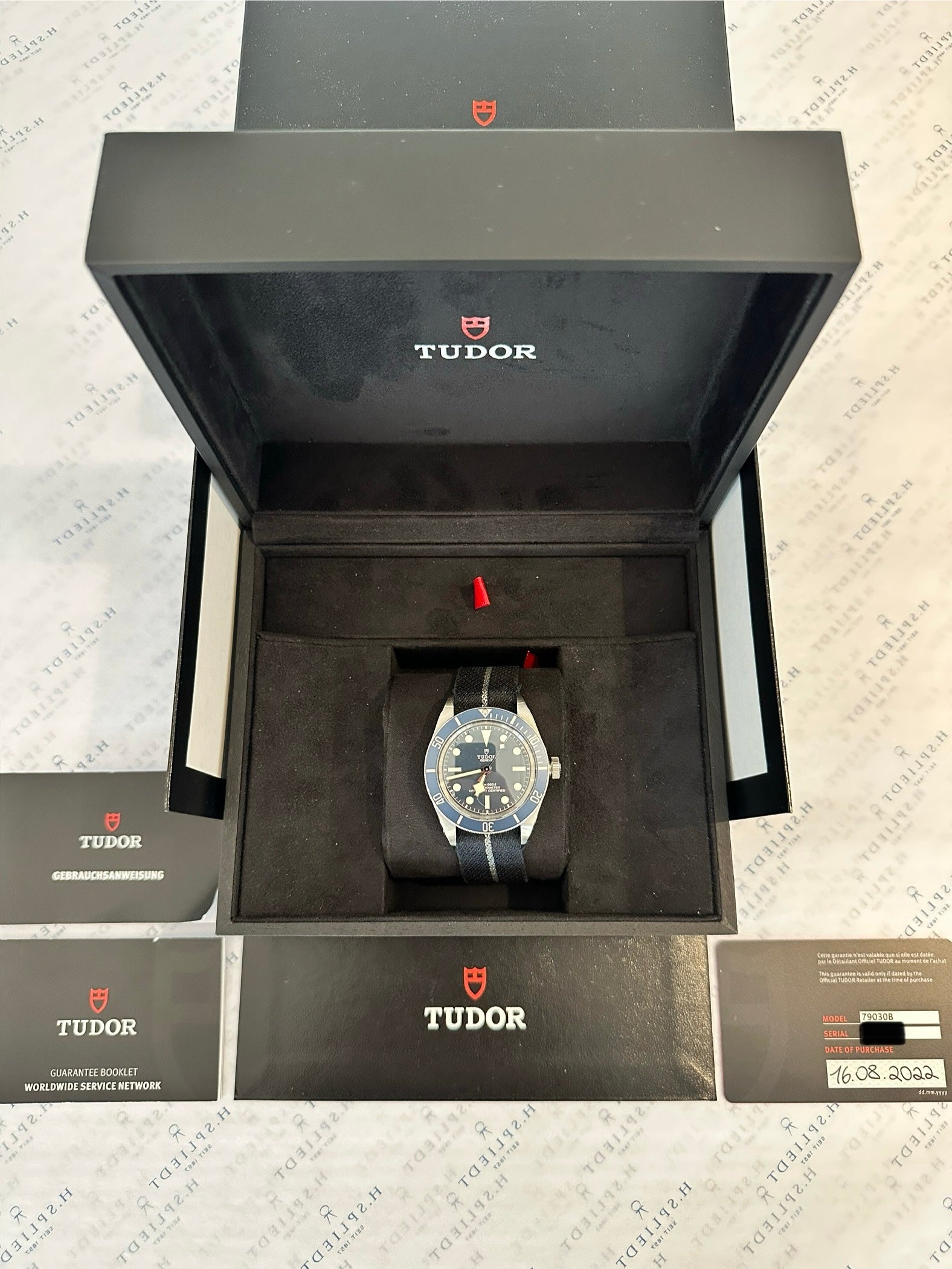 Tudor Black Bay Fifty-Eight Navy Blue (2022) im geöffneten schwarzen Tudor-Etui auf kariertem Papier