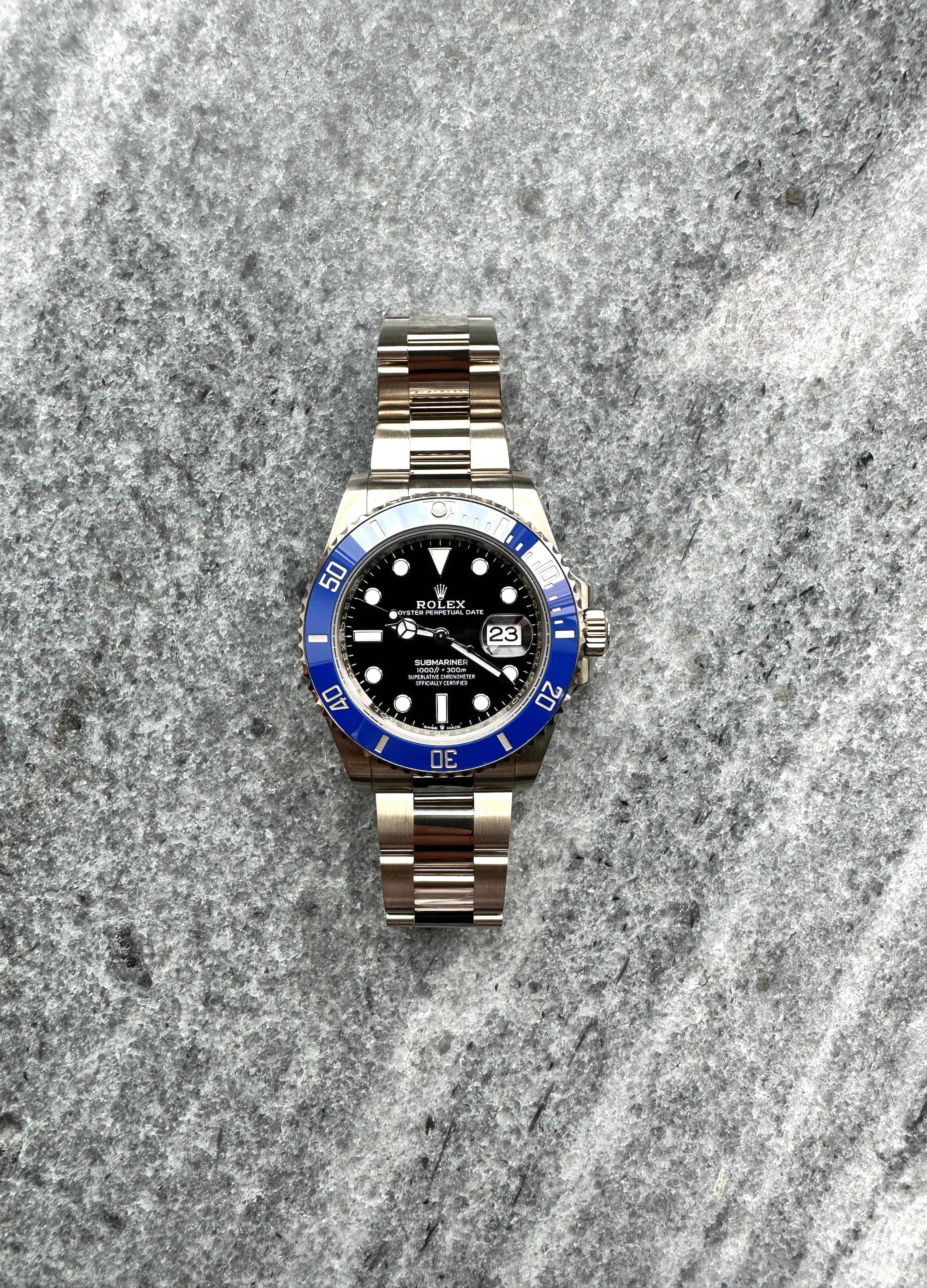 Rolex Submariner Date 126619LB mit blauem Zifferblatt und Keramik-Lünette auf grauem Stein-Untergrund
