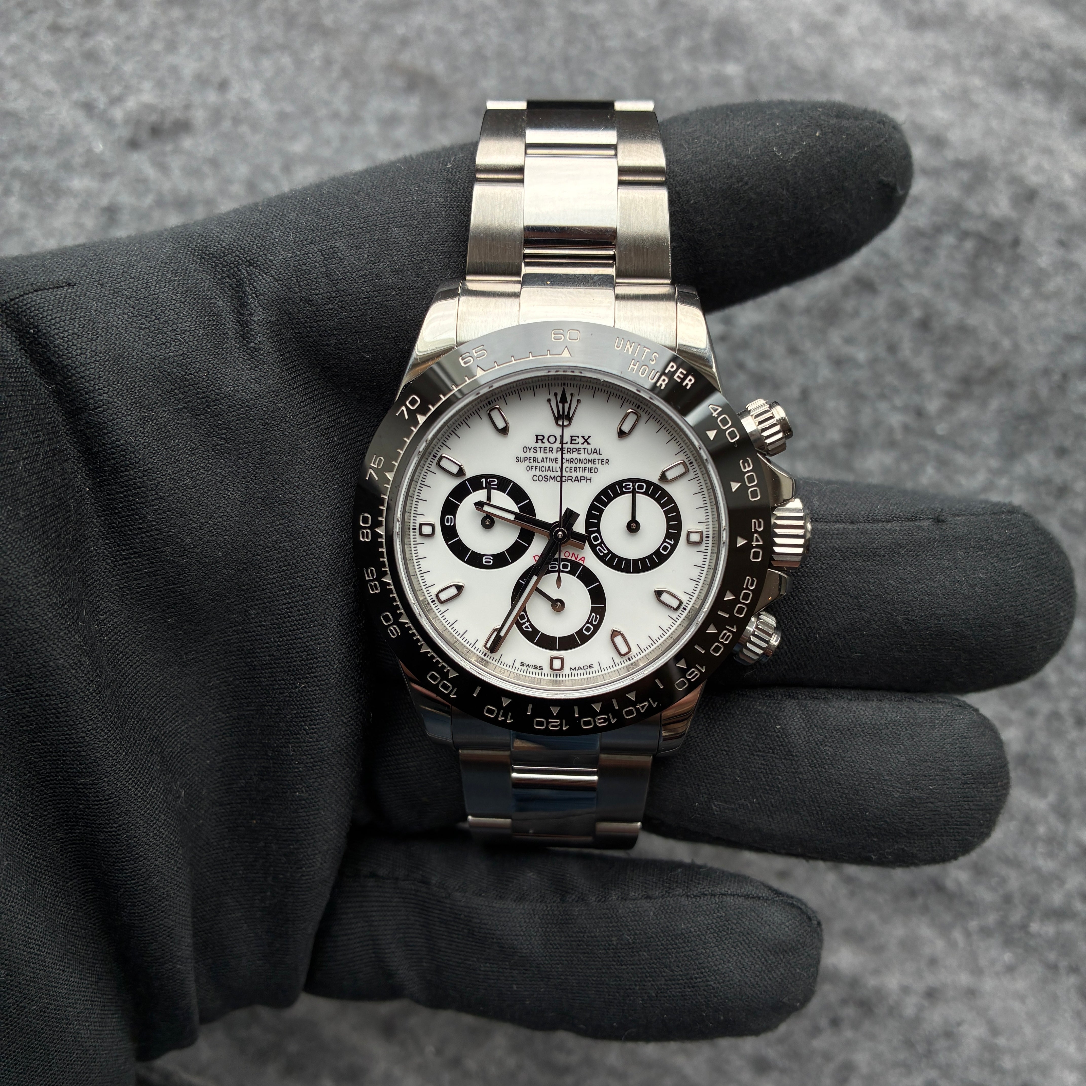 Rolex Daytona Panda Stahl Automatik mit weissem Zifferblatt und schwarzem Lederarmband auf grauem Hintergrund