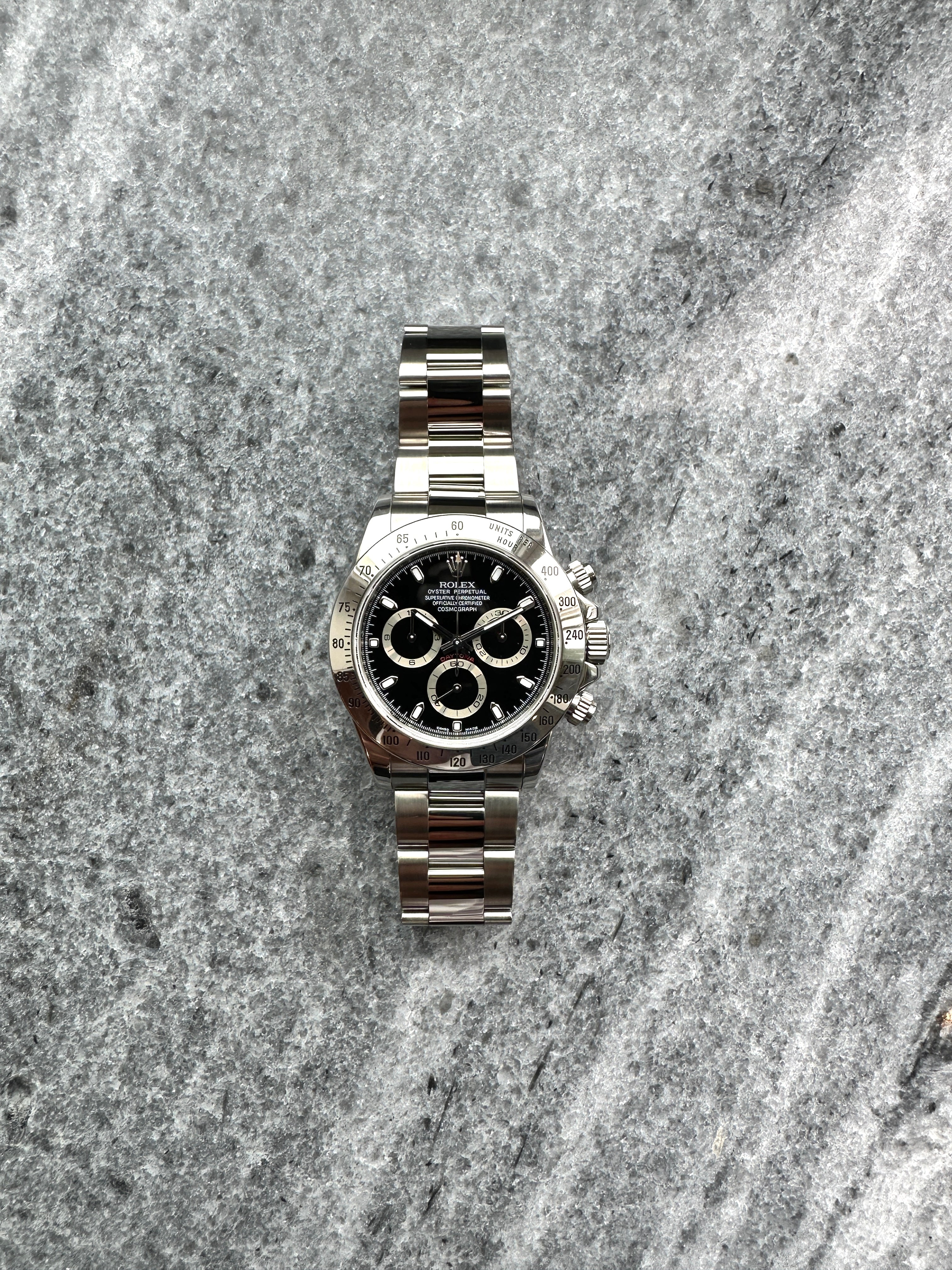 Rolex Daytona 116520 Black mit Edelstahlgehäuse und Automatikwerk auf grauem Stein mit drei Zählern auf dem Zifferblatt
