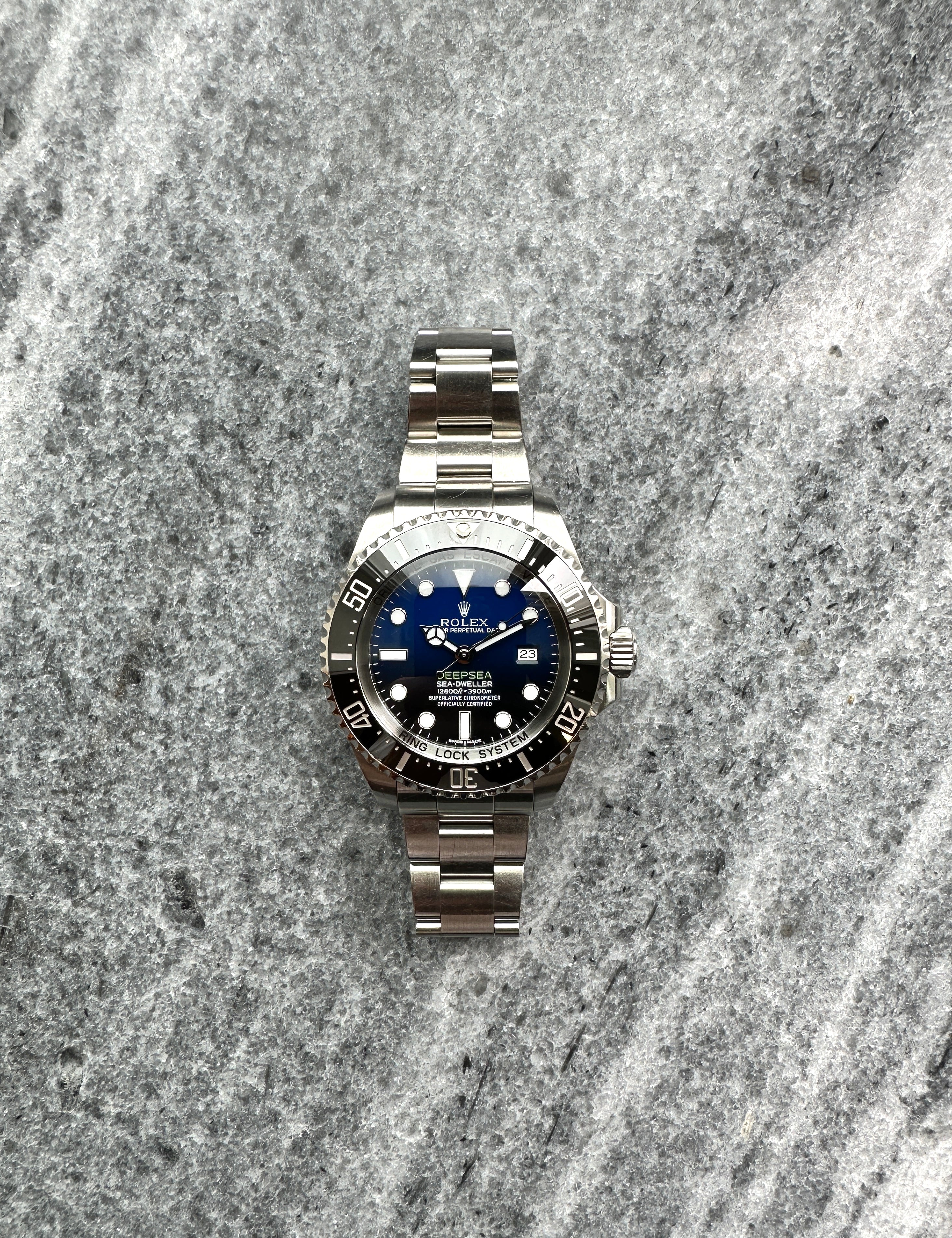 Rolex Deepsea Sea-Dweller James Cameron aus Stahl mit blauem Zifferblatt auf grauem Steinboden
