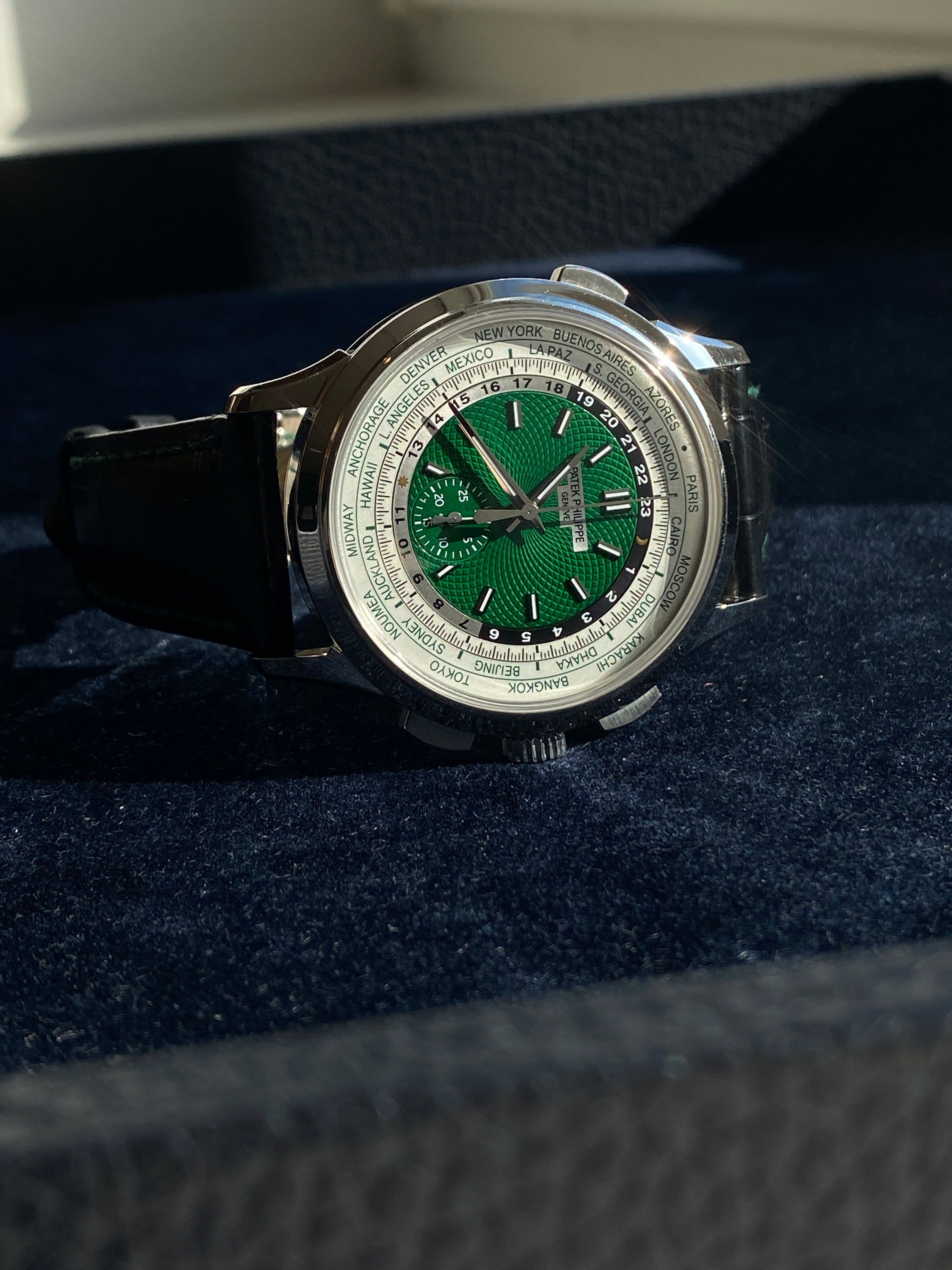 Patek Philippe World Time Flyback Chronograph 5930P-001 in Platin mit grünem Zifferblatt auf dunklem Hintergrund