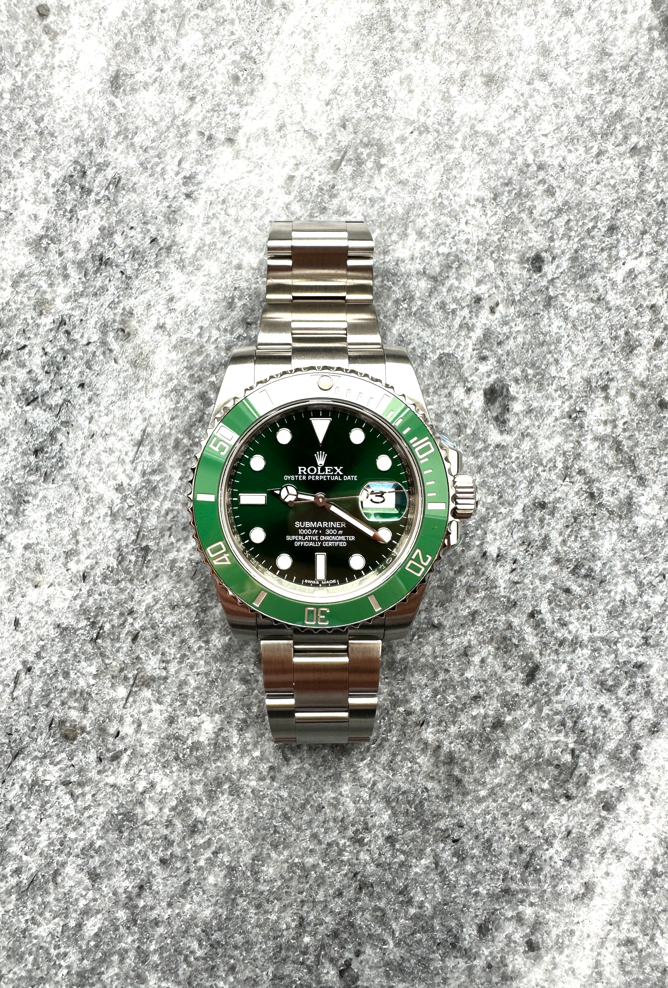 Rolex Submariner Date "Hulk" mit grünem Zifferblatt und Stahlband auf Steinuntergrund