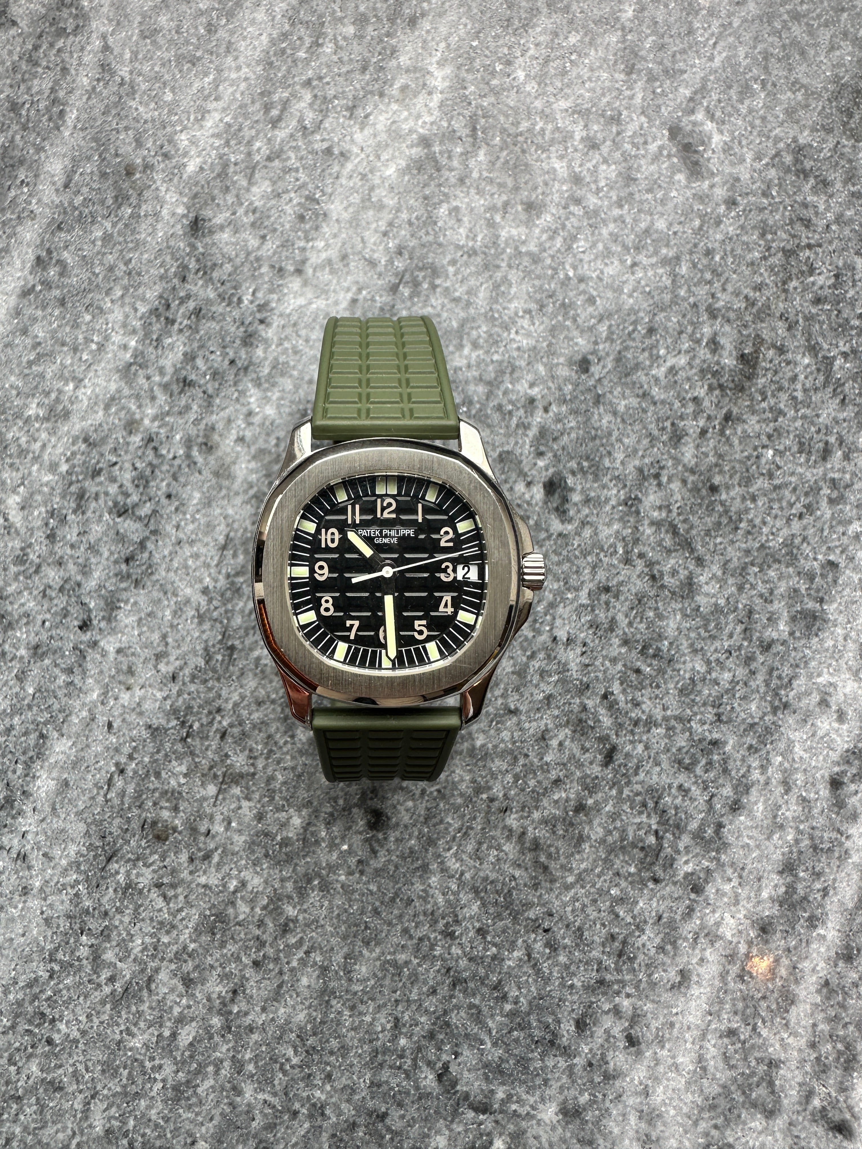 Patek Philippe Aquanaut 38mm Edelstahl mit grünem Kautschukband auf grauem Steingrund