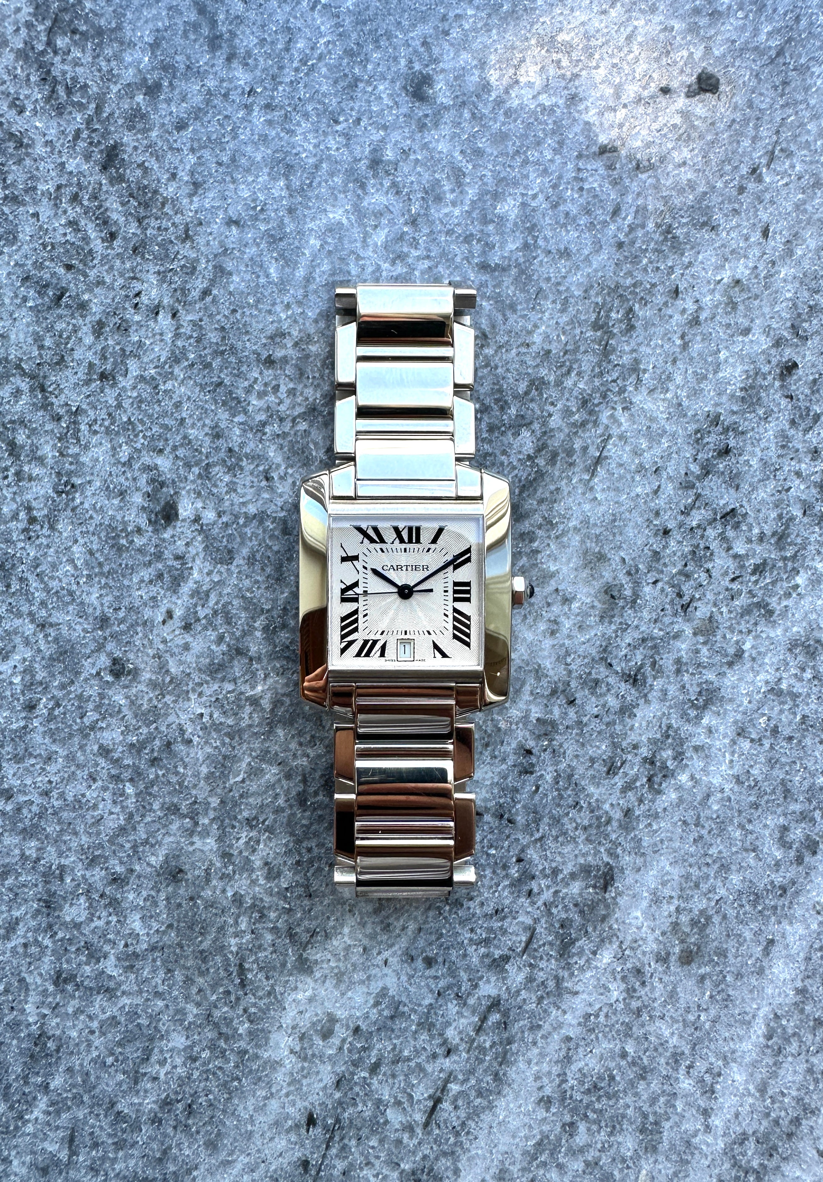 Eine Cartier Tank Francaise Weißgold Automatik Ref. 2366 auf steinigem Hintergrund