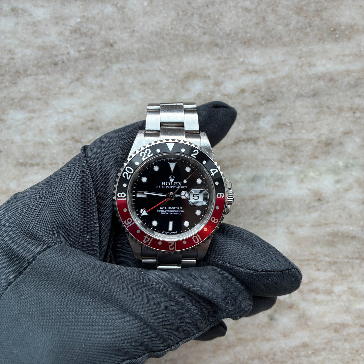 Rolex GMT-Master II / T-Series / Coke / Box & Papers / 2004, Vorderansicht mit Zifferblatt, Krone und Armband vor neutralem Hintergrund