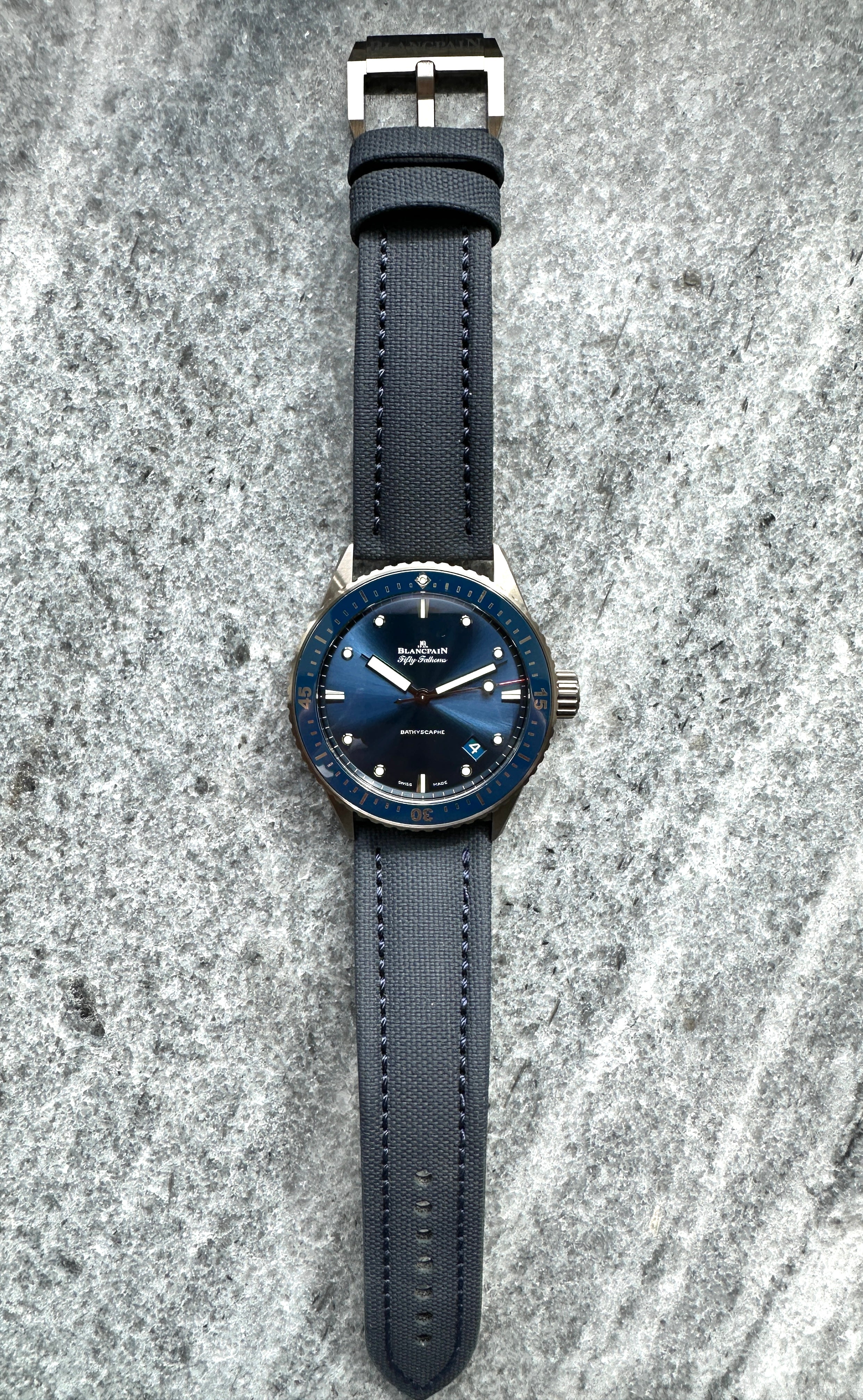 Blancpain Fifty Fathoms Bathyscaphe Keramik mit blauem Zifferblatt und dunkelgrauem Armband auf Steingrund
