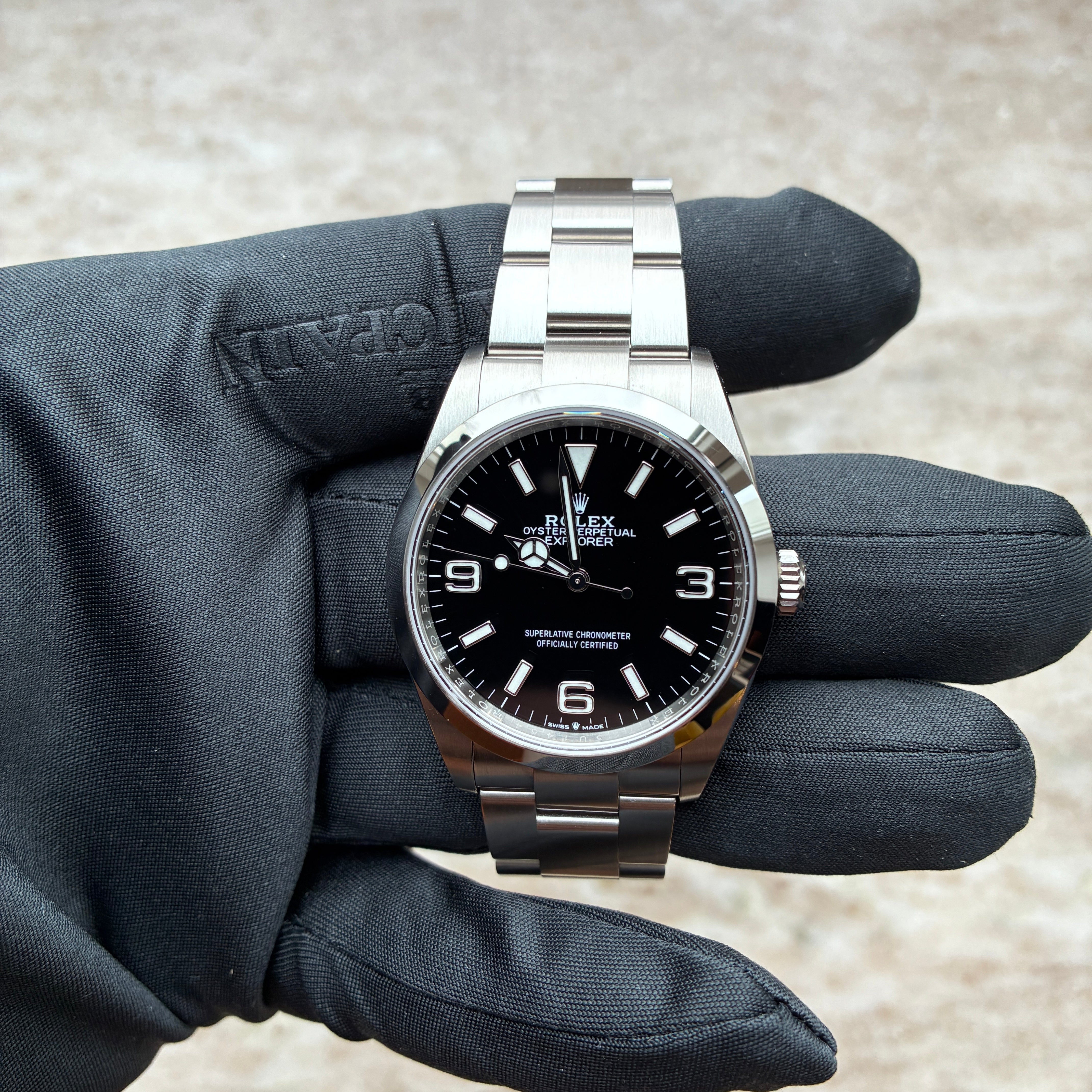 Rolex Explorer mit schwarzem Zifferblatt, gehalten von einer Hand mit schwarzer behandschuhter Hand
