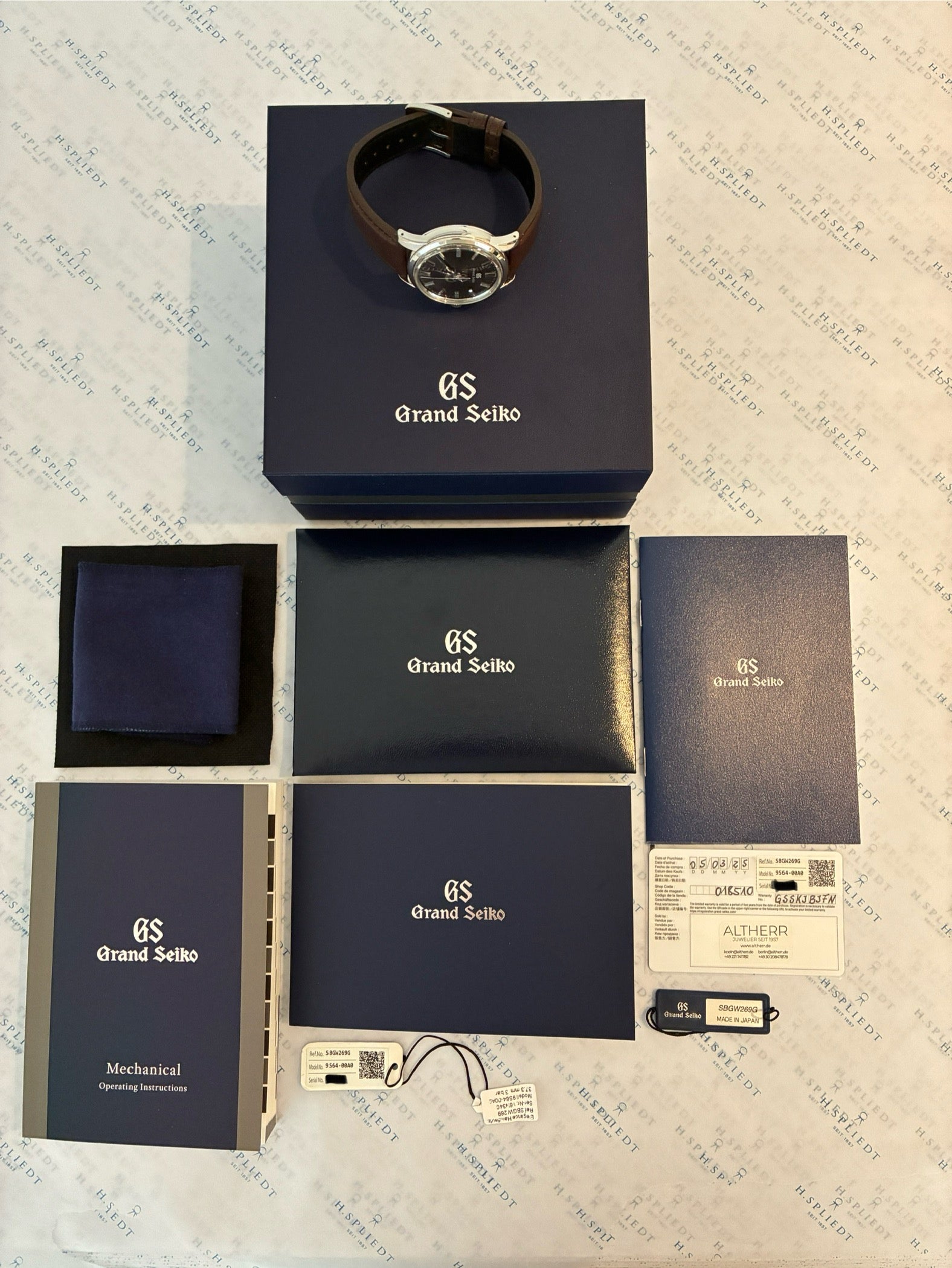 Grand Seiko Heritage Automatik in Edelstahlausführung mit braunem Lederarmband und Zubehör auf Unterlage