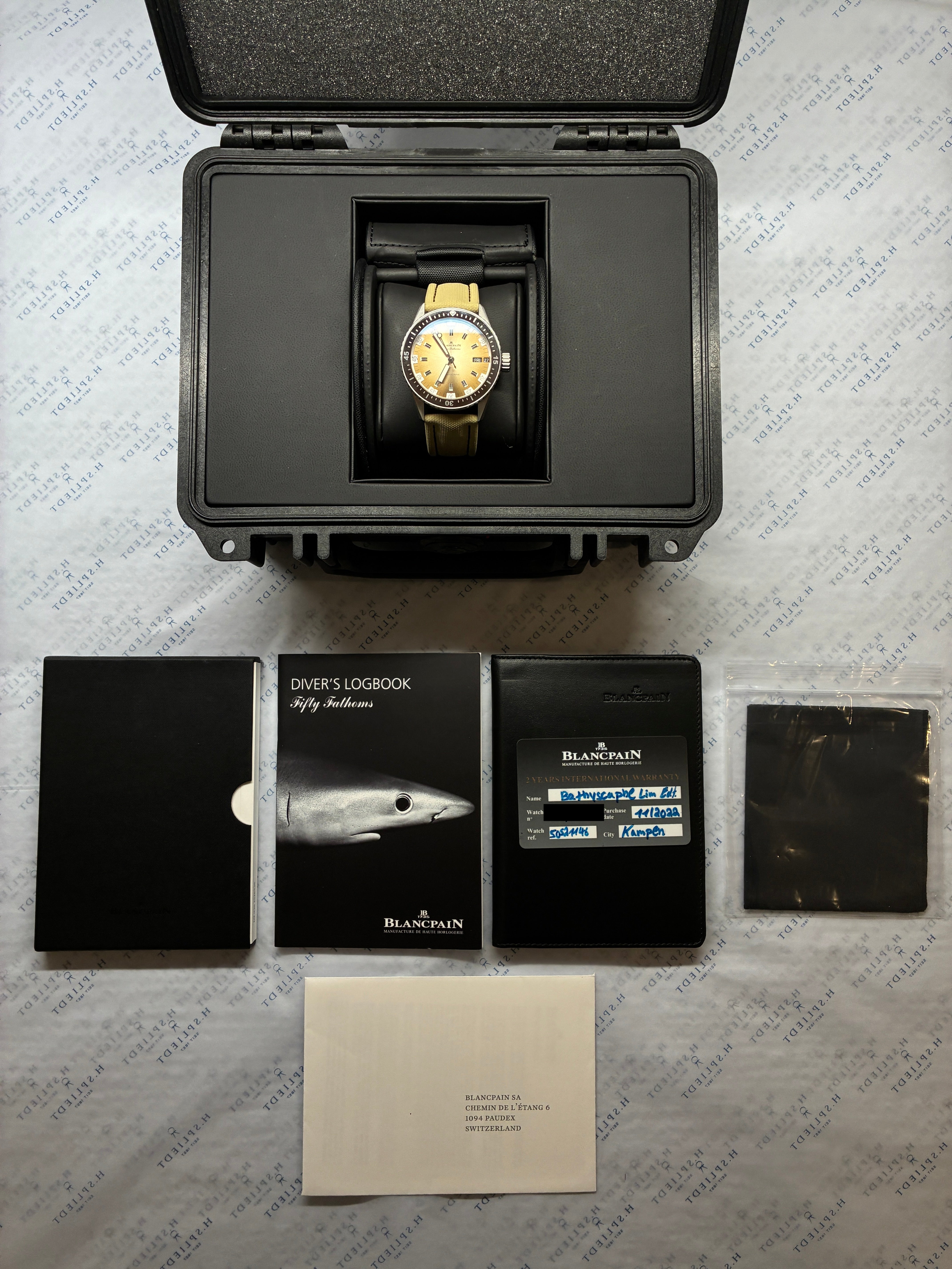 Blancpain Fifty Fathoms Bathyscaphe in schwarzer Hülle mit Zubehör auf gemustertem Hintergrund