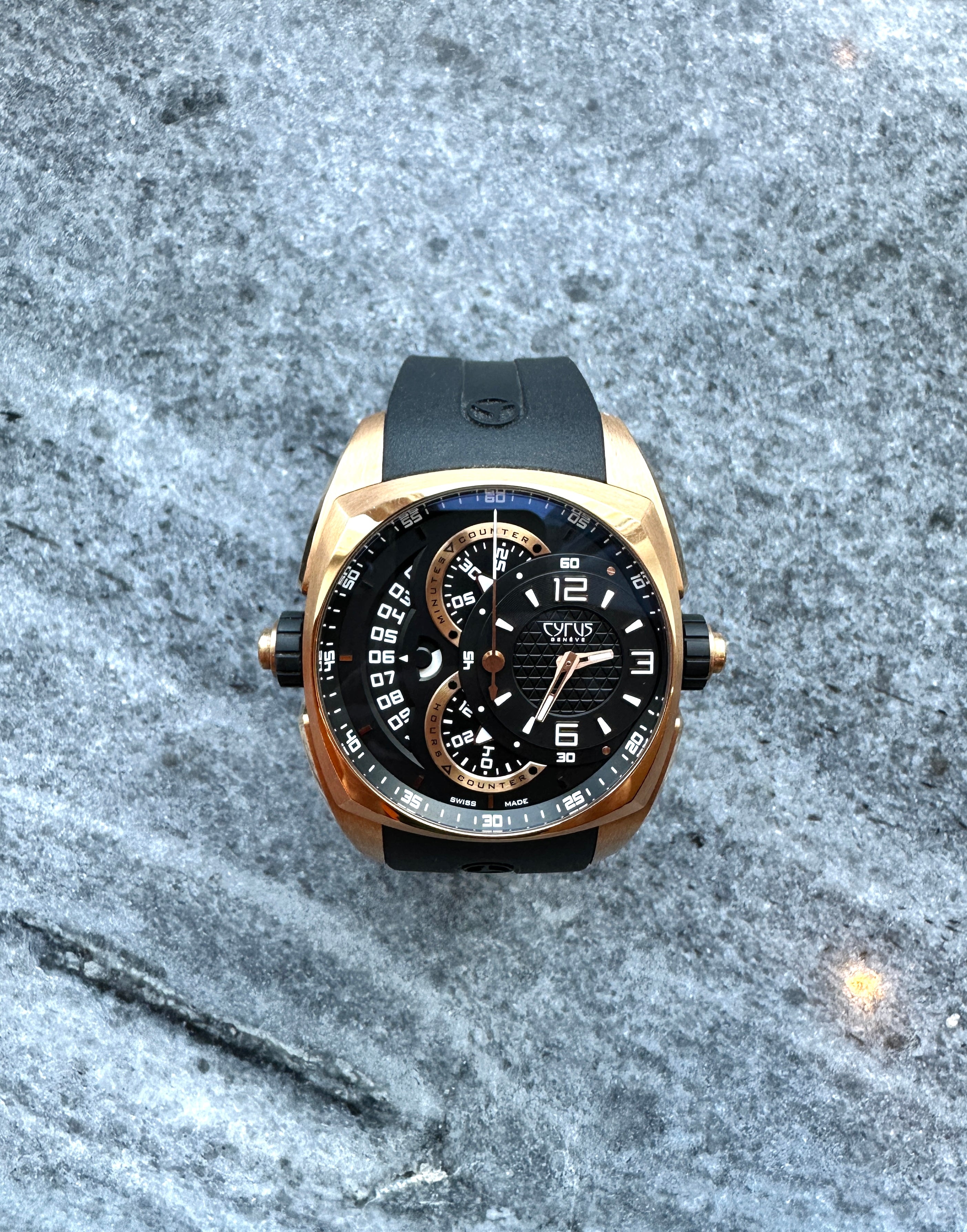 Cyrus Klepcys Chronograph Roségold 5N Automatik mit schwarzem Armband auf steinigem Grund