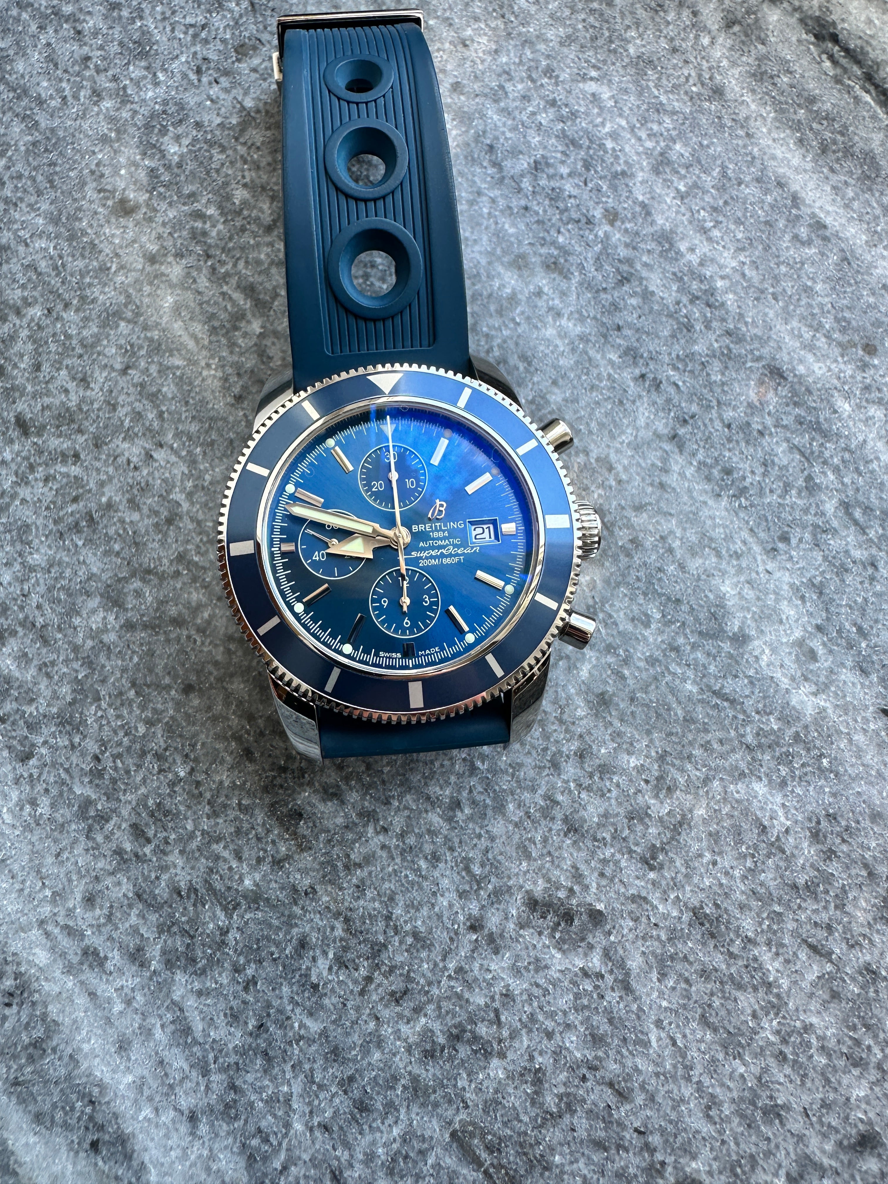 Breitling Superocean Heritage Chronograph mit blauem Zifferblatt und Kautschukarmband auf grauem Hintergrund