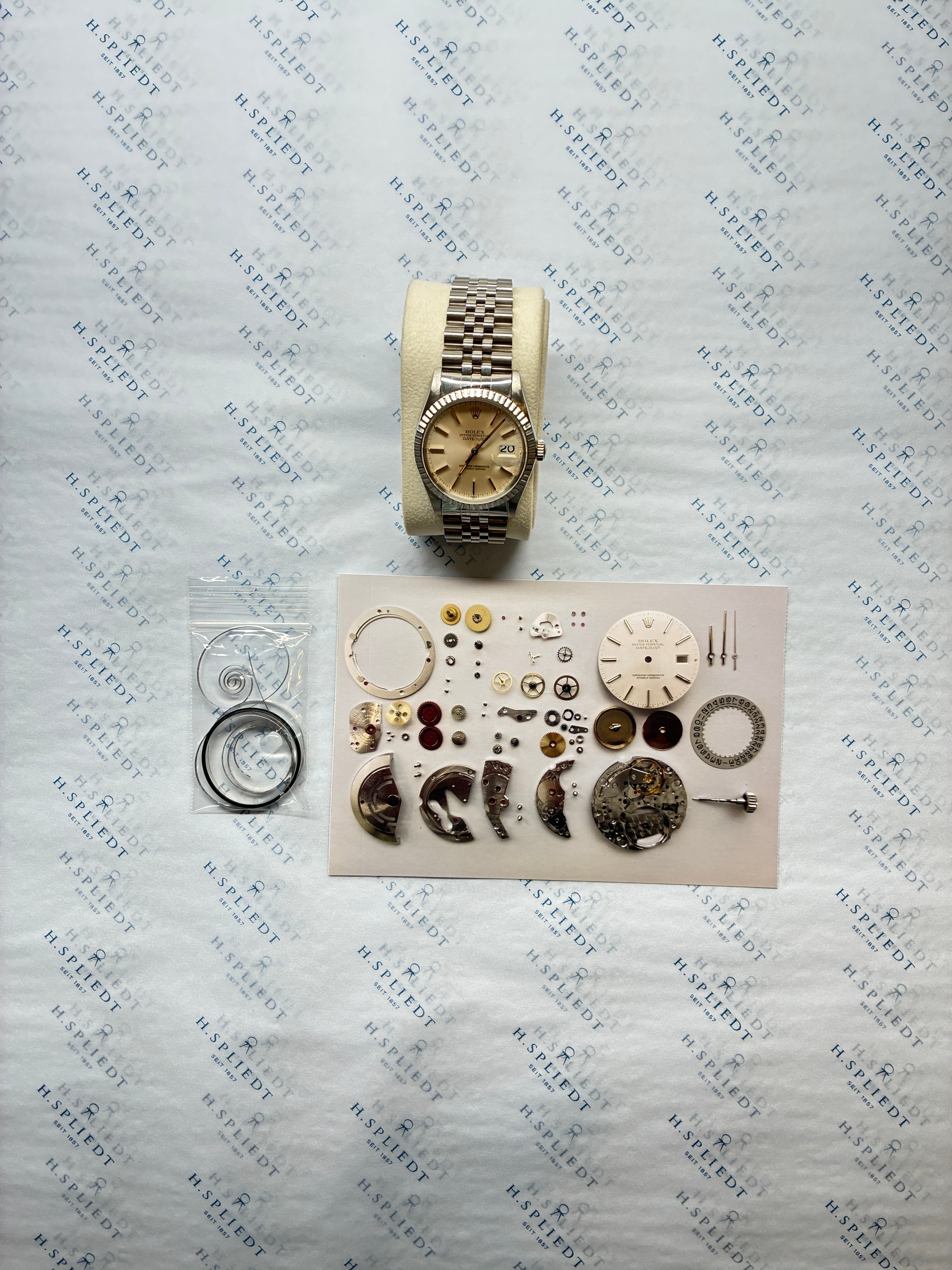 Rolex Datejust 36mm Edelstahl mit silbernem Zifferblatt und Datum, zerlegte Uhr und Ersatzteile auf geprägtem Hintergrund