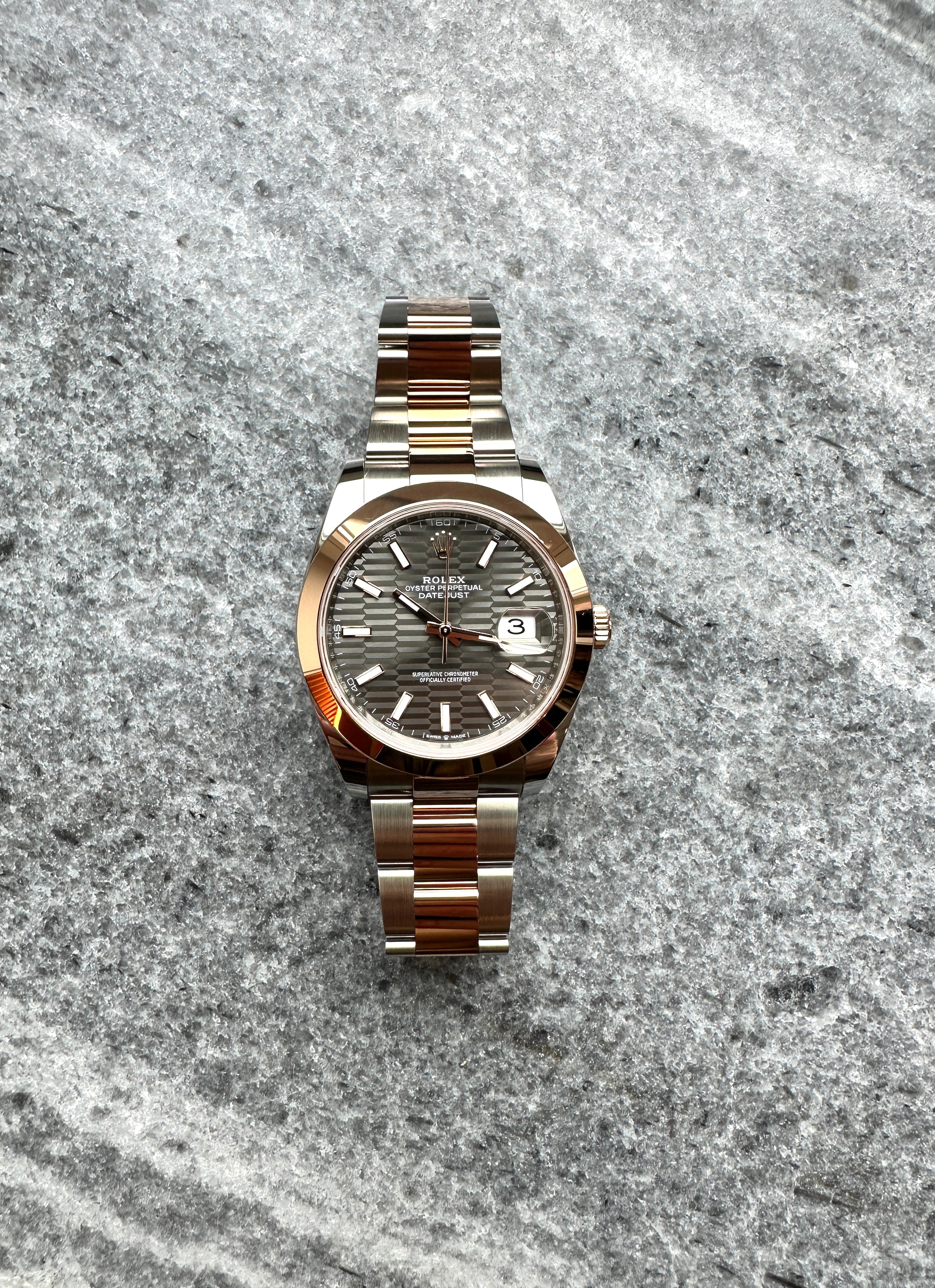 Rolex Datejust 41 mit HONEYCOMB-Zifferblatt aus Stahl und Gold im Anschnitt auf grauem Untergrund