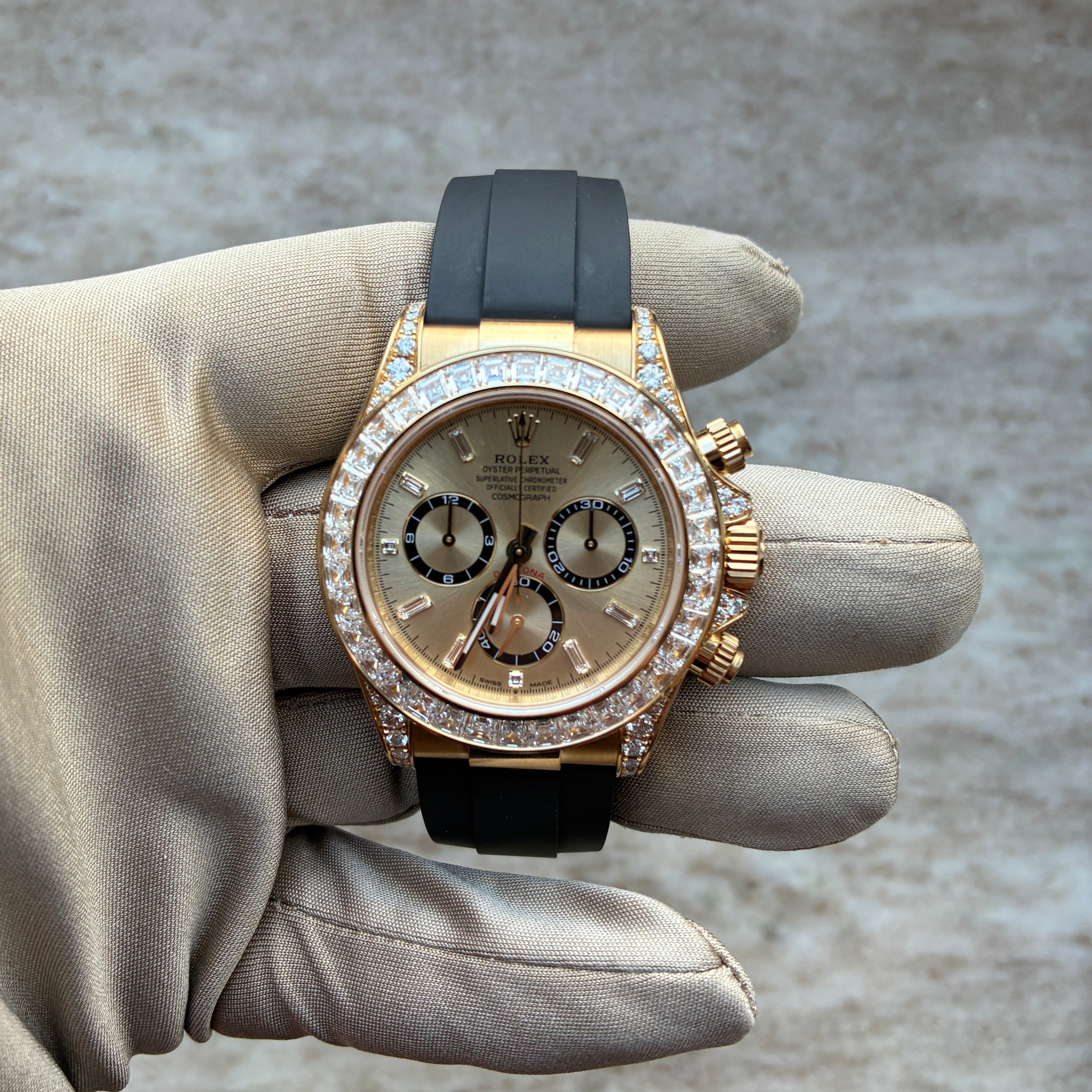 Rolex Cosmograph Daytona mit Diamantlünette, gelbes Gold und schwarzes Kautschukarmband wird in der Hand gehalten