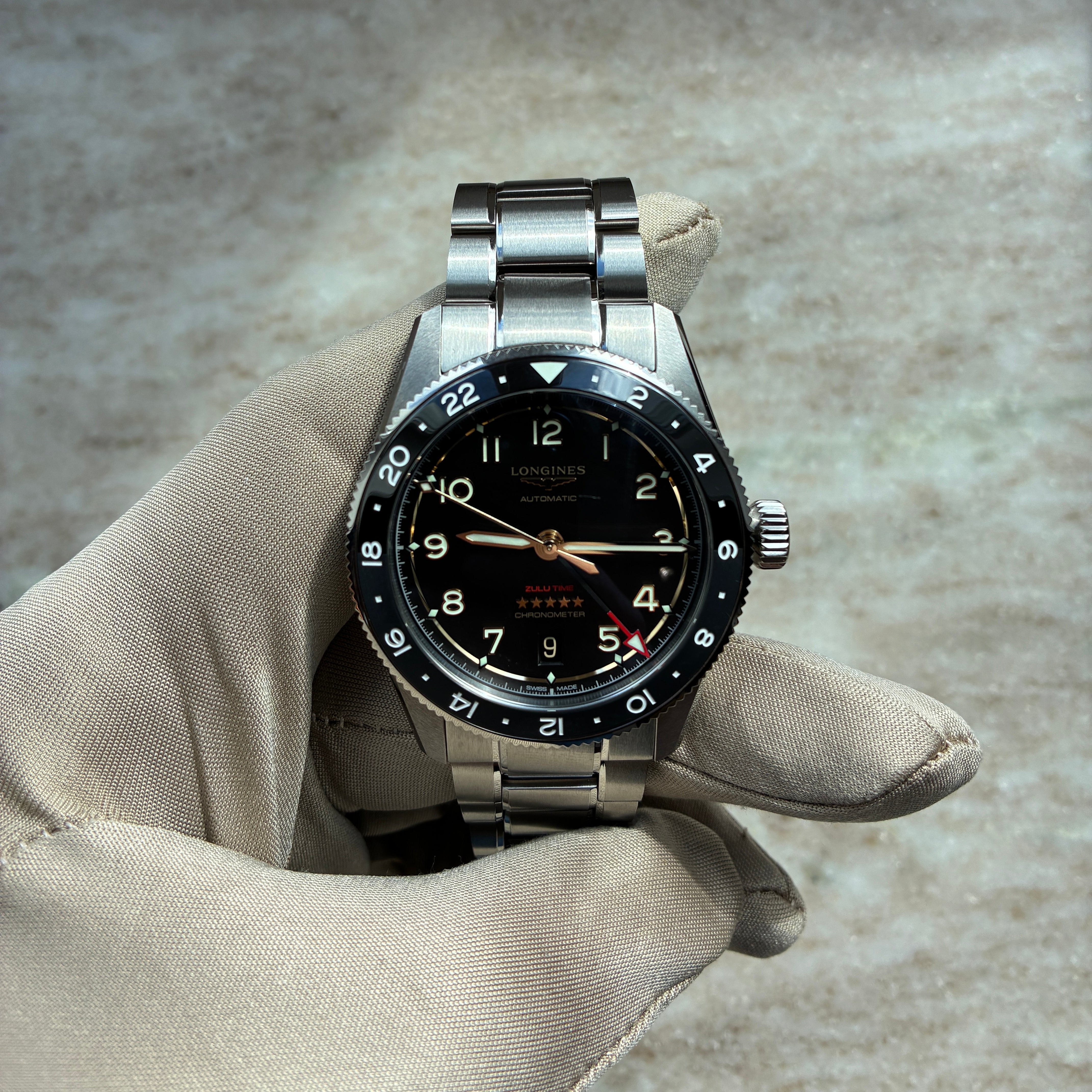 Longines Spirit Zulu Time 39mm Automatikuhr mit schwarzem Zifferblatt und Stahlarmband, auf hellem Hintergrund liegend