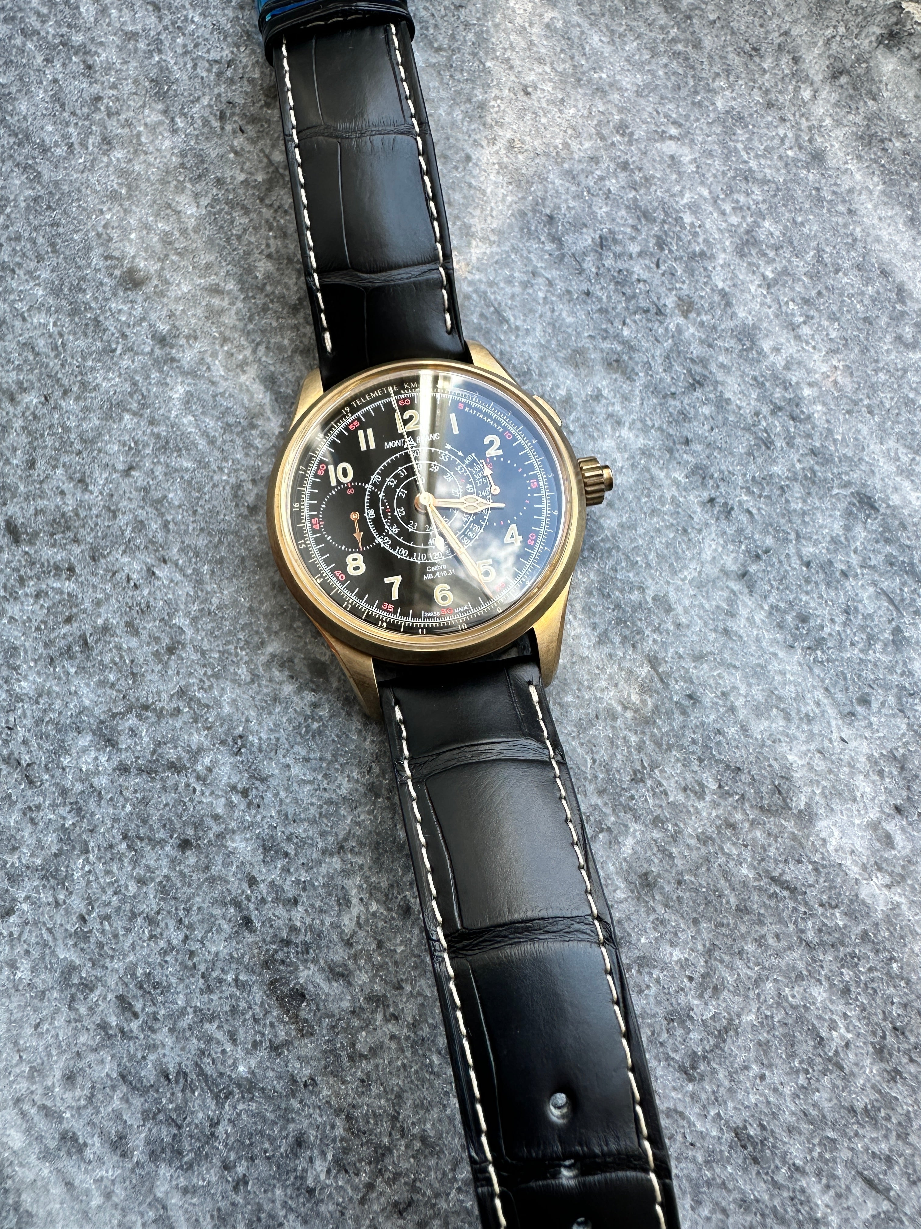 Montblanc 1858 Split-seconds Chronograph aus Bronze mit schwarzem Alligatorlederband auf grauem Steinboden