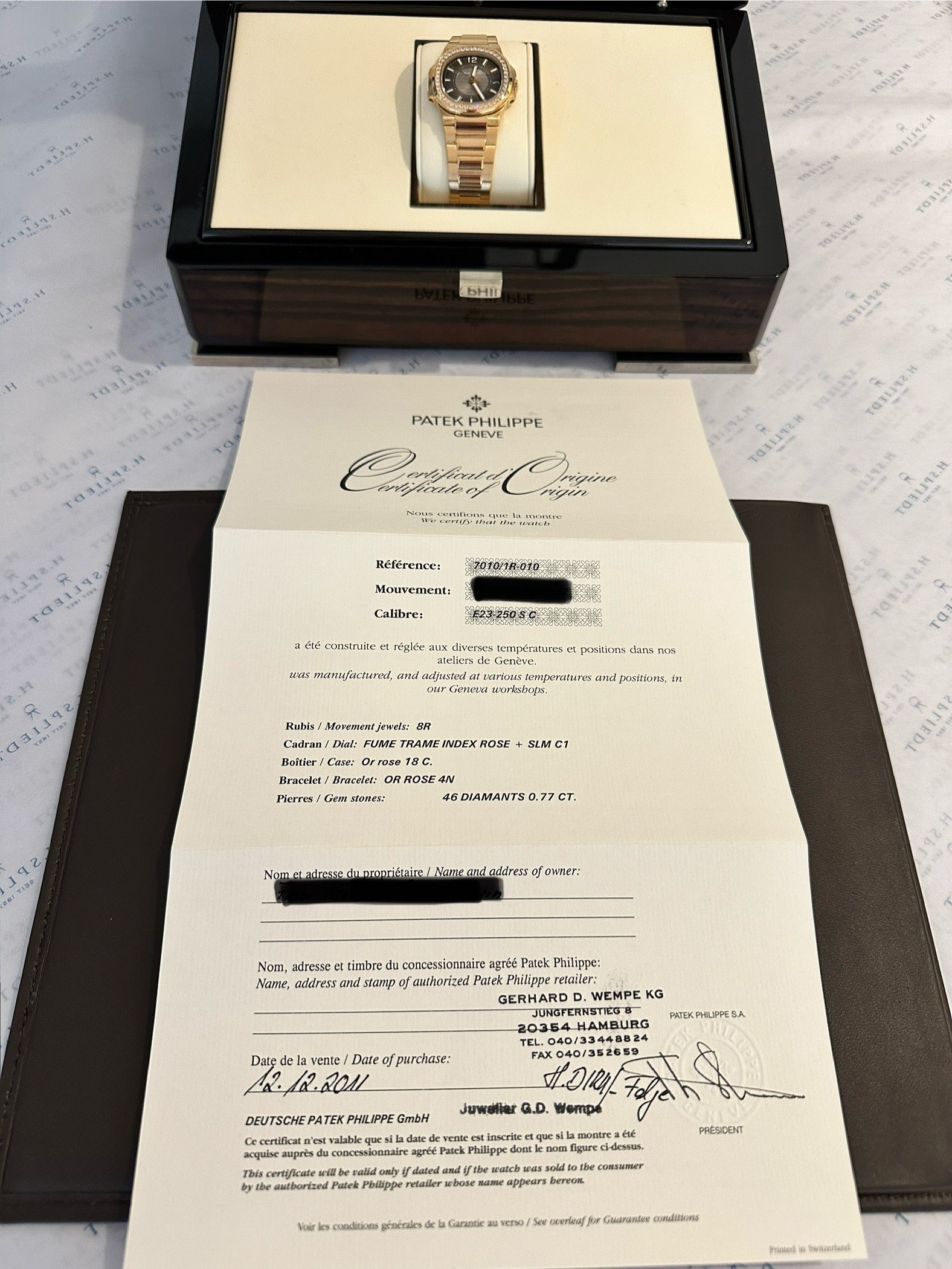 Patek Philippe Nautilus Lady 7010 Roségold mit Diamanten im Inneren einer offenen Holzkiste neben dem Kaufzertifikat