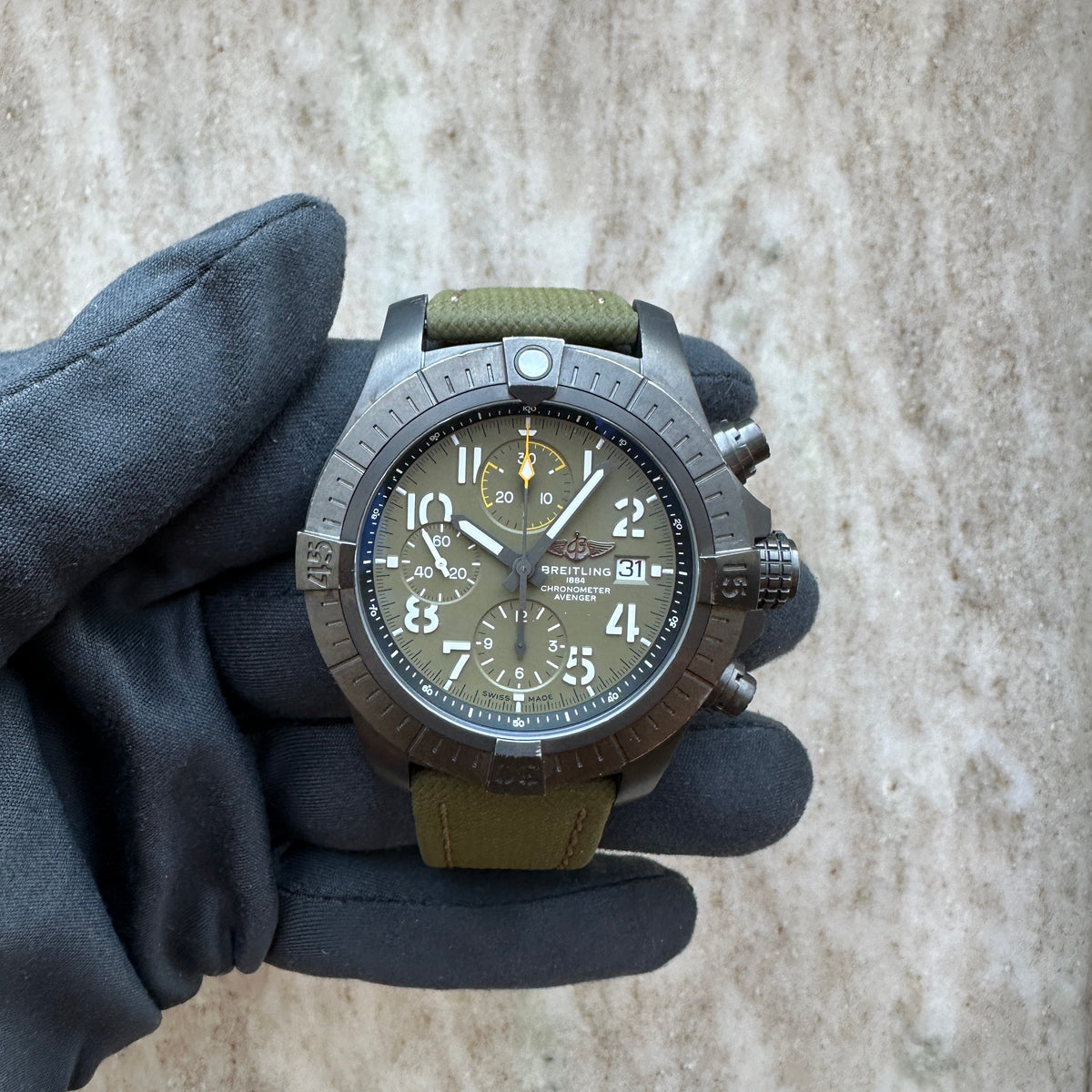 Breitling Avenger Chronograph 45 Night Mission / Box and Paper / 2022, Vorderansicht mit Zifferblatt, Krone und Drückern vor neutralem Hintergrund