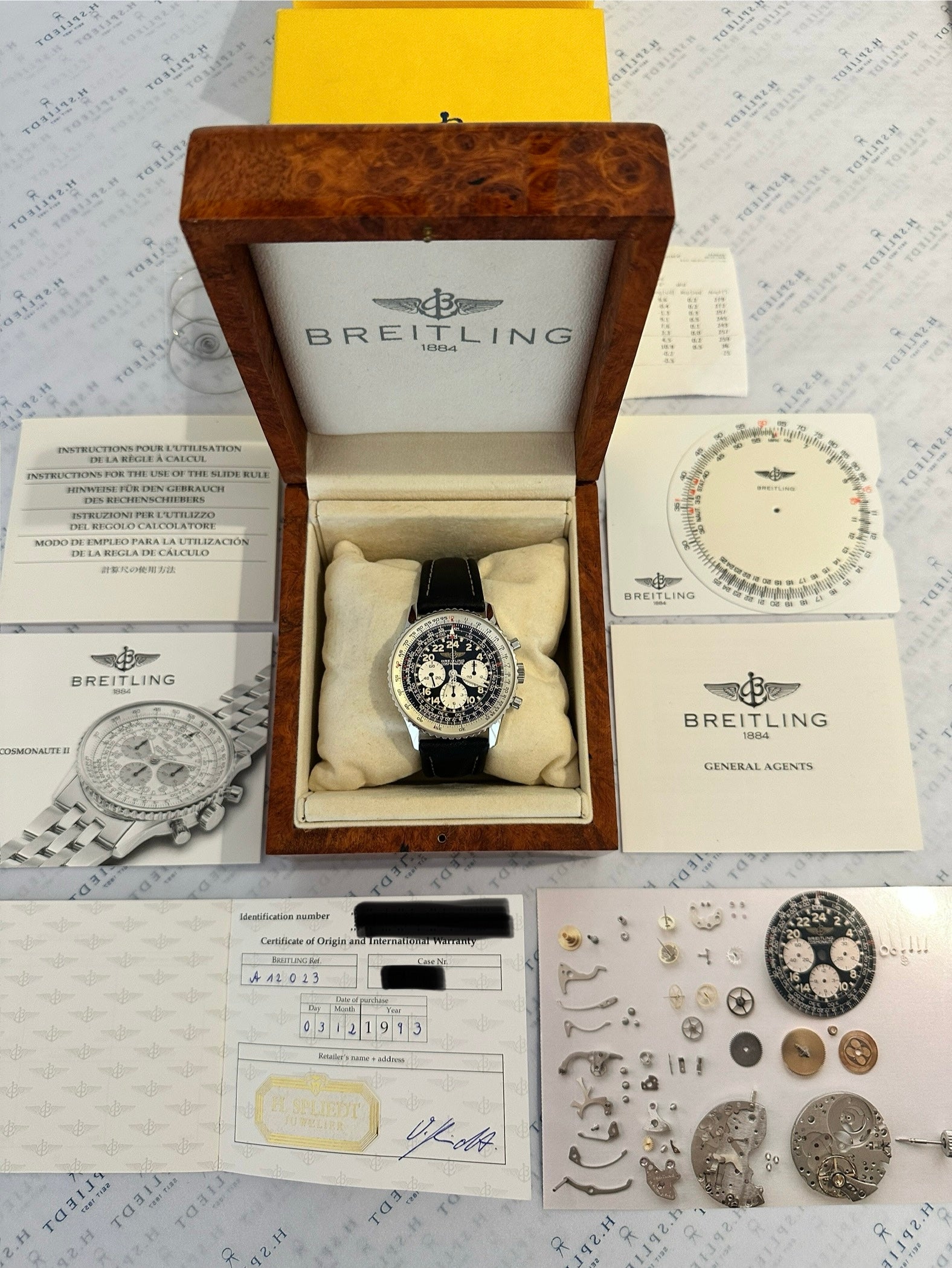 Breitling Navitimer Cosmonaute A12023 im Holzdisplay mit Papieren und Uhrwerksteilen
