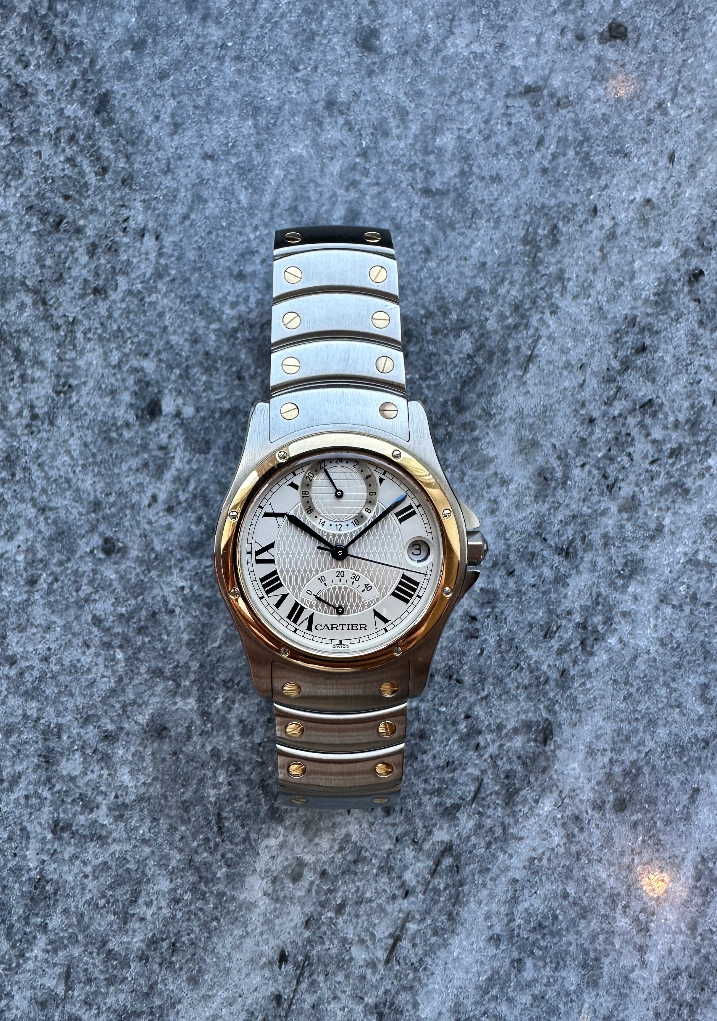 Cartier Santos Ronde 150th Automatic 1997 Stahl Gold Herrenuhr mit silbernem Zifferblatt auf steinigem Untergrund