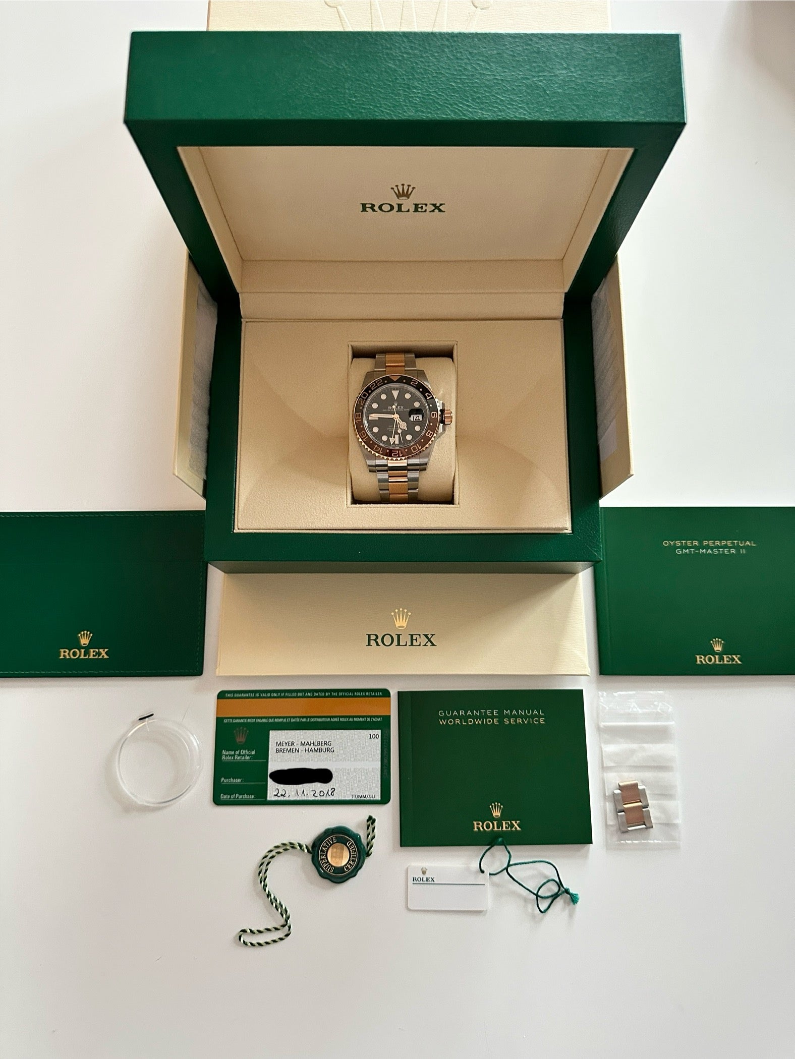 Rolex GMT-Master II Rootbeer im geöffneten Kasten mit Zubehör auf weißem Hintergrund