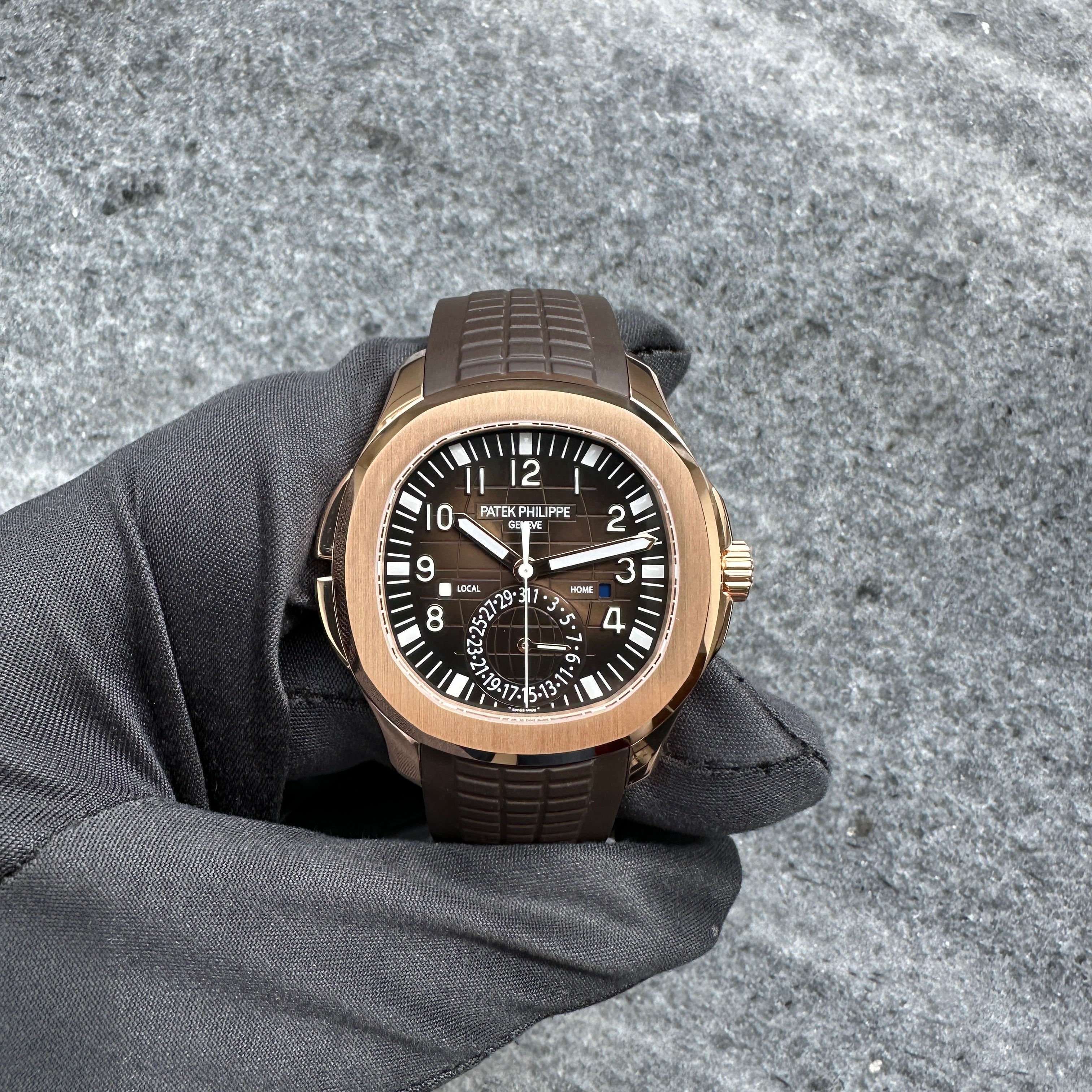 Patek Philippe Aquanaut Travel Time 5164R Roségold auf grauem Untergrund, Nahaufnahme von vorne