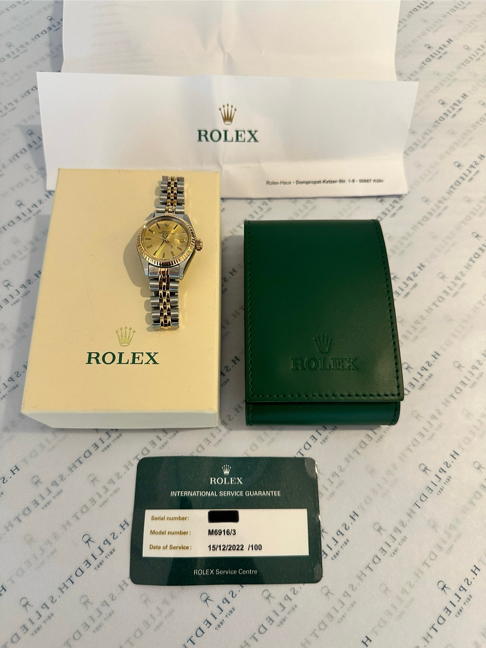 Rolex Lady-Datejust 26 mm Stahl/Gold mit Dokumenten auf bedrucktem Hintergrund