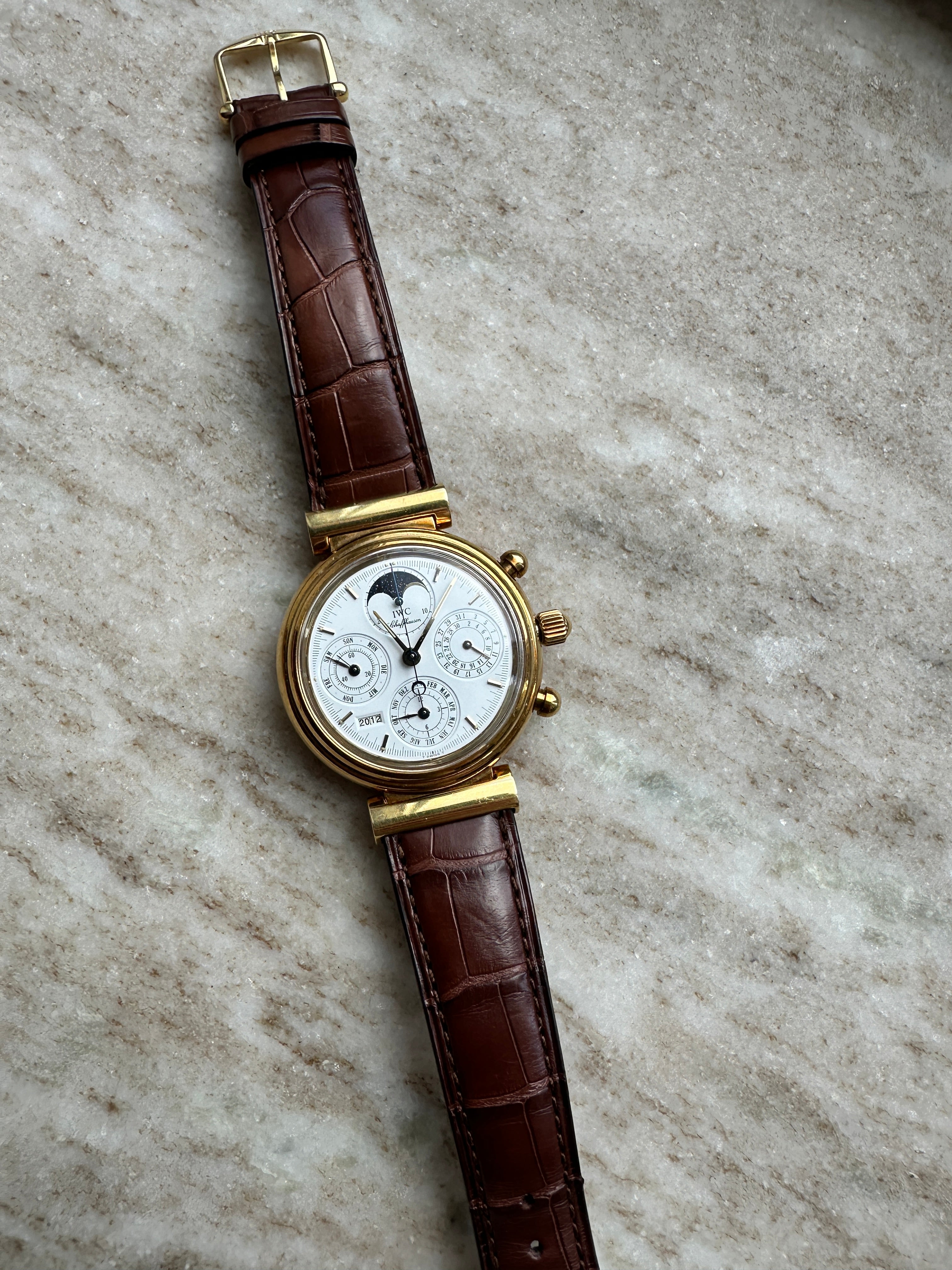 IWC Da Vinci Perpetual Calendar Gelbgold mit braunem Krokodillederarmband auf Marmorhintergrund