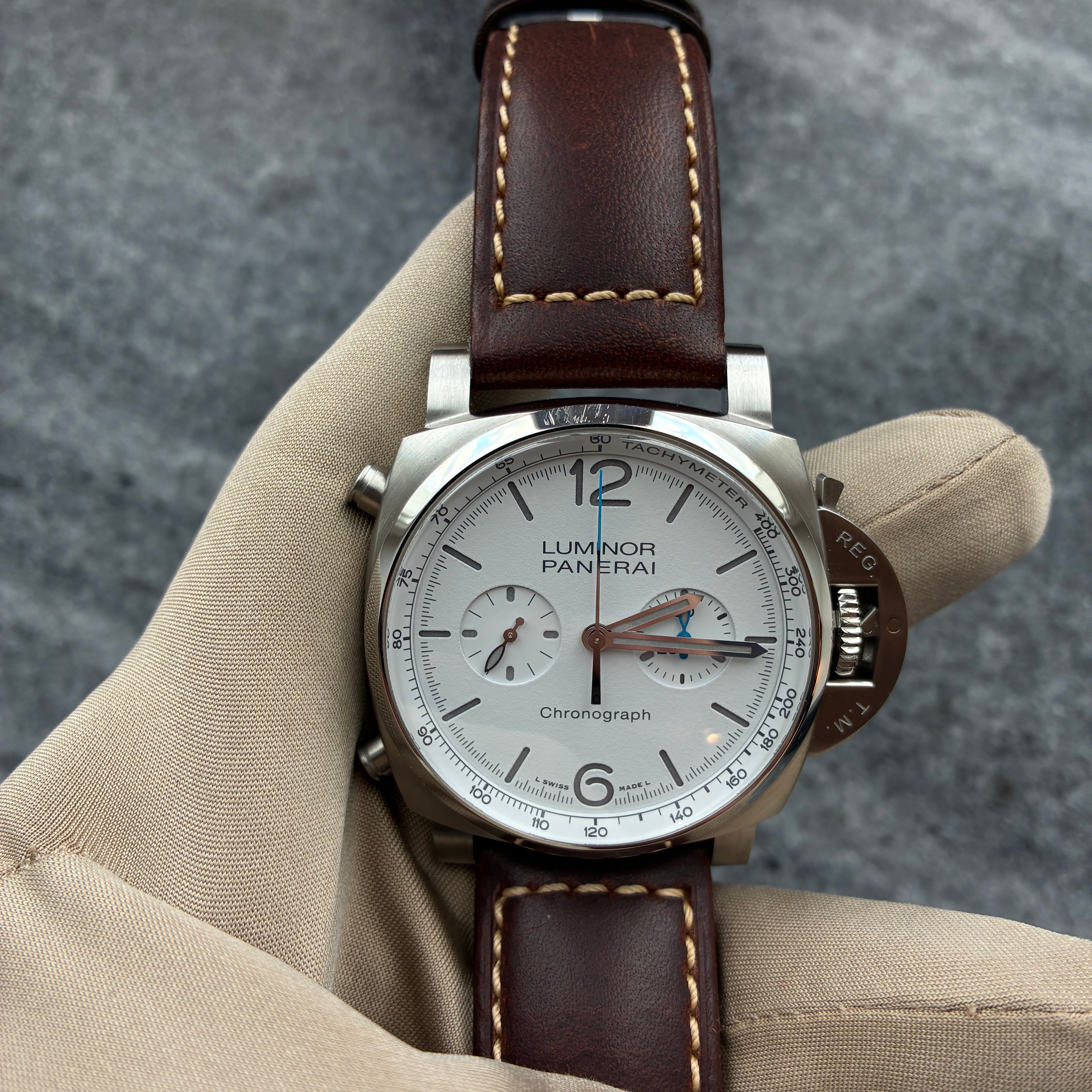 Panerai Luminor Chrono 44 mm Edelstahl Automatik mit braunem Lederarmband auf grauem Hintergrund