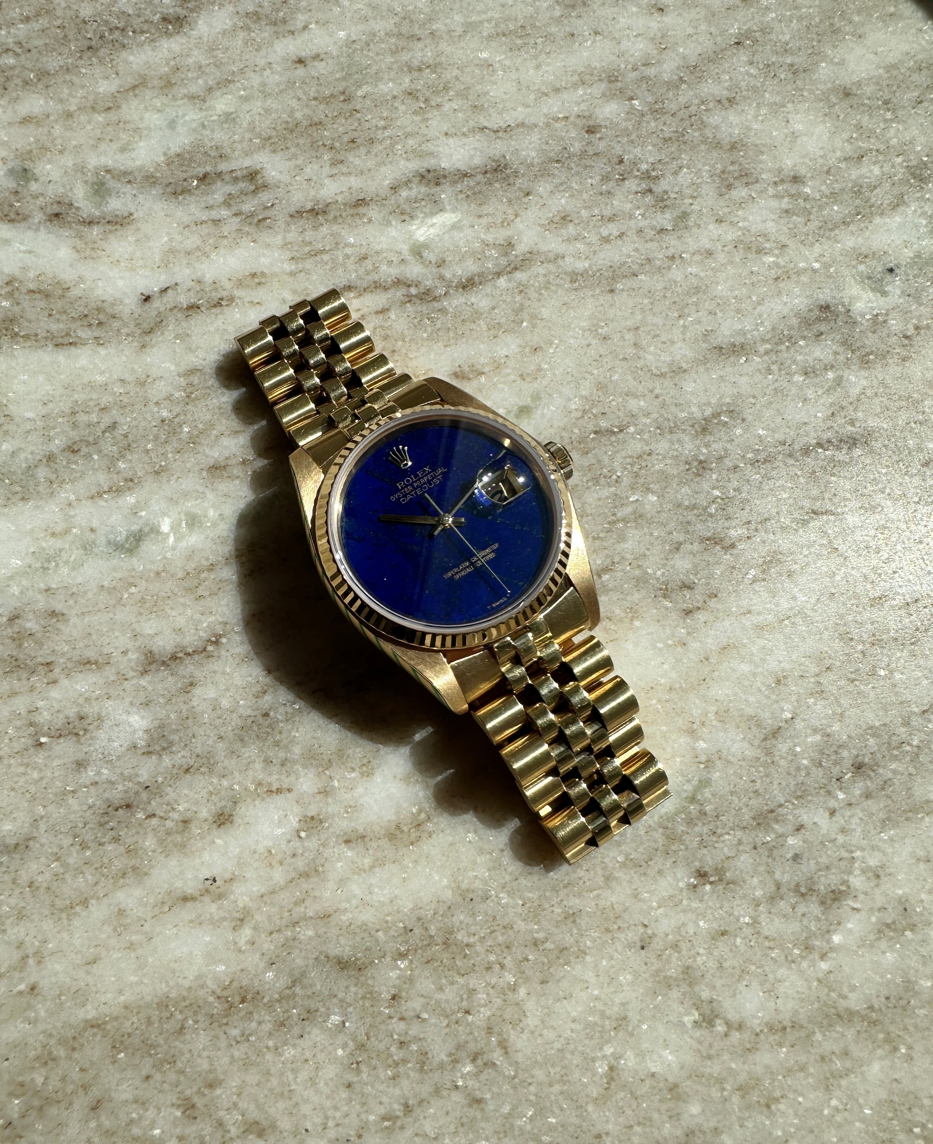 Rolex Datejust 36 Lapis Lazuli aus Gelbgold von 1979 auf hellem Marmorboden