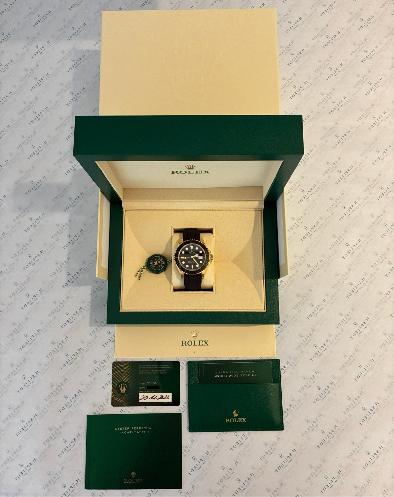 Eine Rolex Yacht-Master 42 Gelbgold mit schwarzem Armband liegt in ihrer grünen Originalverpackung