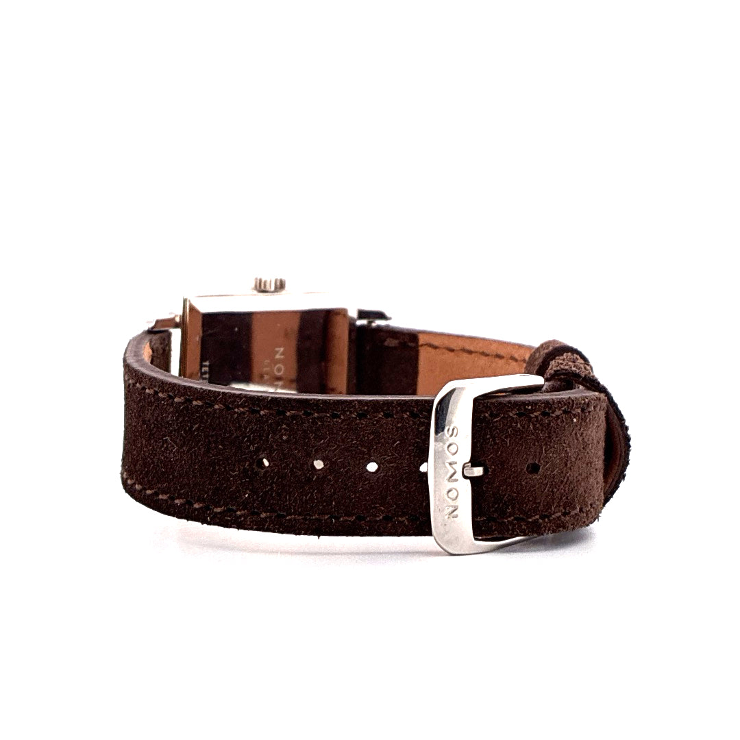 Seitenansicht einer Nomos Tetra 27 Uhr mit braunem Wildlederarmband und Edelstahlschließe