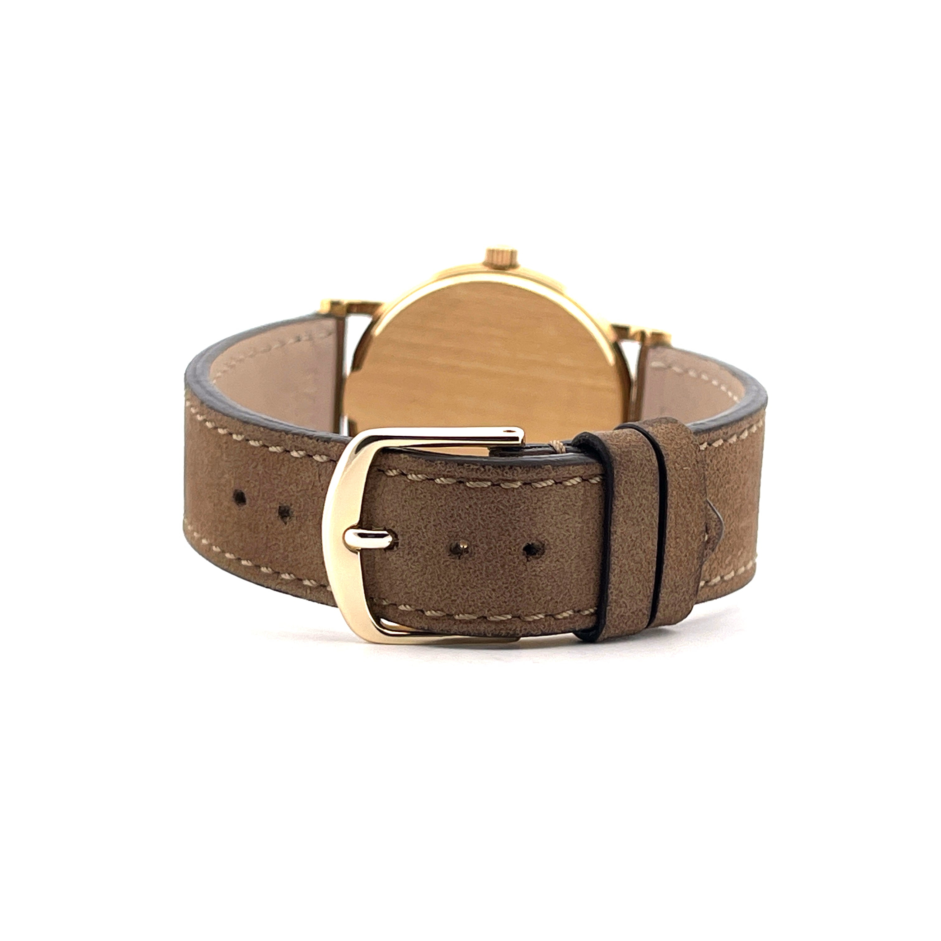 Rückseite einer Patek Philippe Calatrava mit goldenem Gehäuse und braunem Lederarmband mit Gürtelschnalle