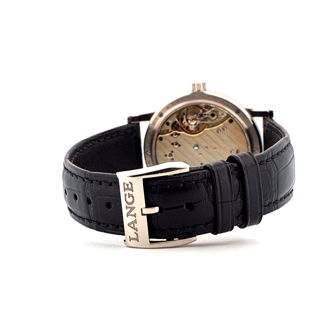 A. Lange & Söhne Lange 1 im Detail der schwarzen Krokodilleder-Schließe aus Weißgold mit der Aufschrift "LANGE" auf weißem Hintergrund