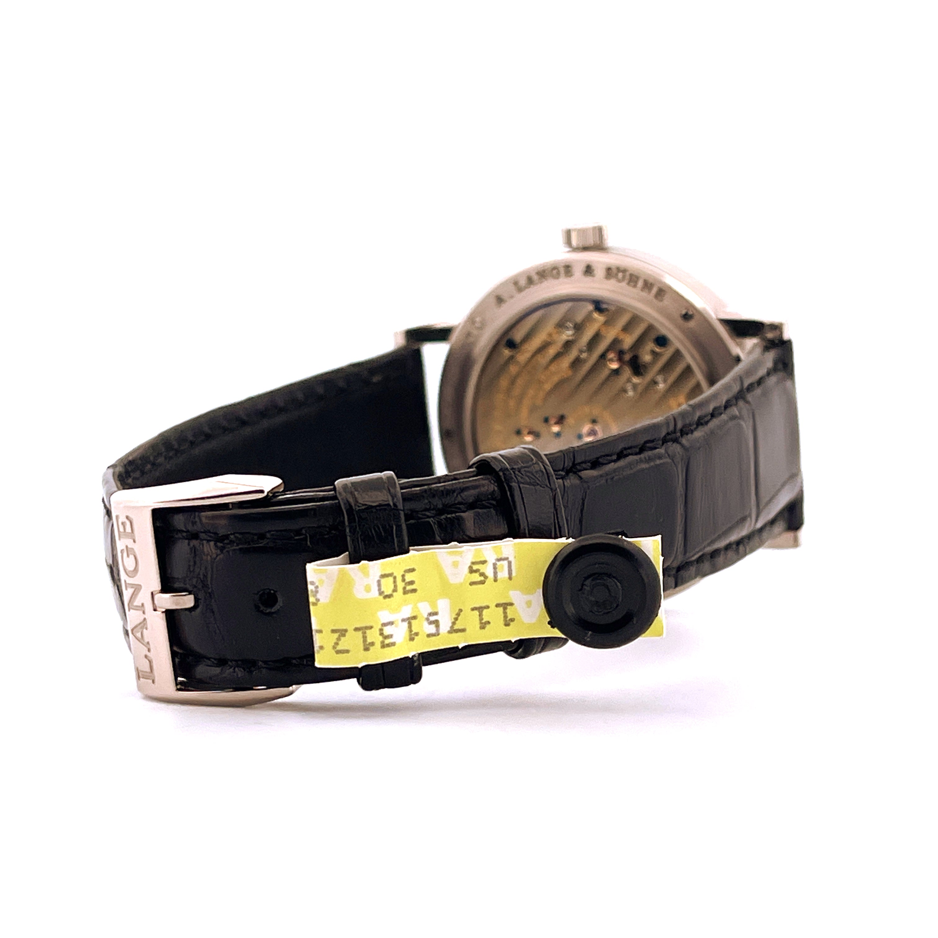 Seitenansicht einer A. Lange & Söhne 1815 Uhr mit schwarzem Lederarmband und Sicherheitsetikett
