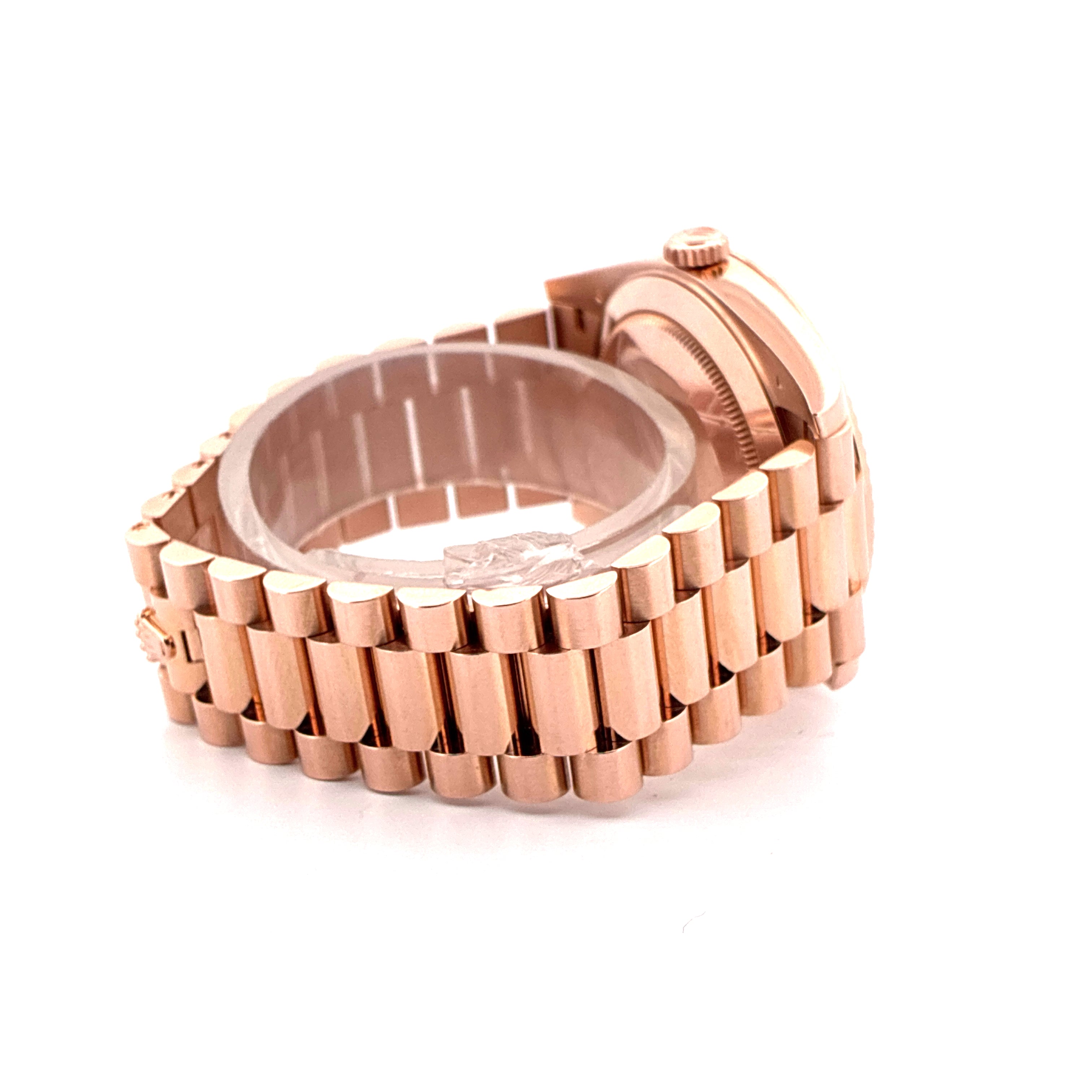 Seitenansicht einer Roségold Rolex Day-Date 40 Uhr auf weißem Hintergrund mit Band und Gehäuse im Fokus