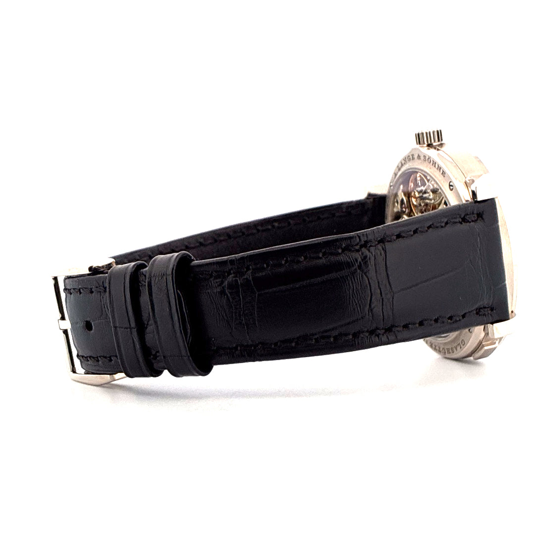 Seitenansicht einer A. Lange & Söhne Lange 1 in Weißgold mit schwarzem Krokodillederarmband und silberner Schließe auf weißem Hintergrund