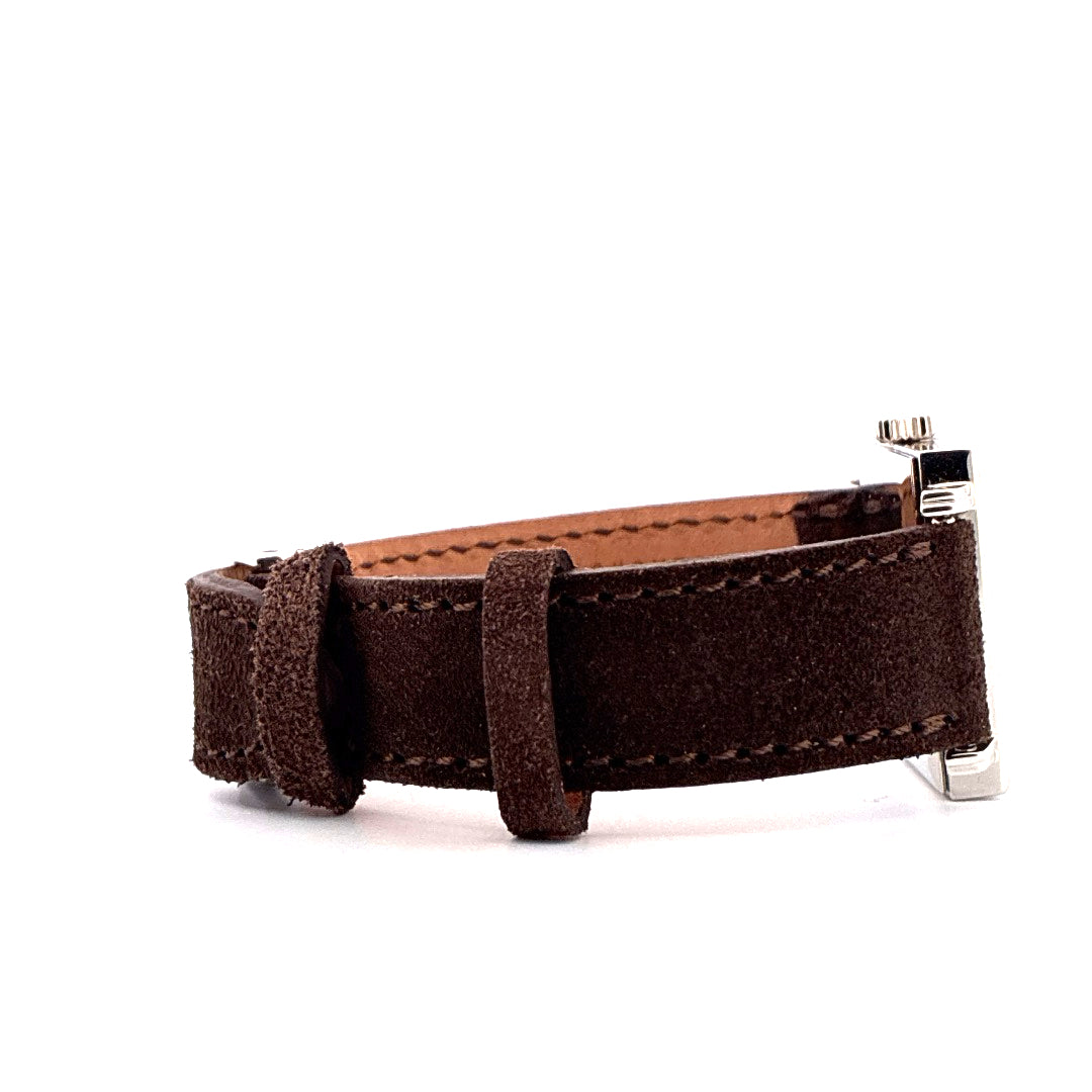 Nomos Tetra 27 Karat Like Unworn Detailansicht eines braunen Wildlederarmbands mit polierter Edelstahlschließe auf weißem…