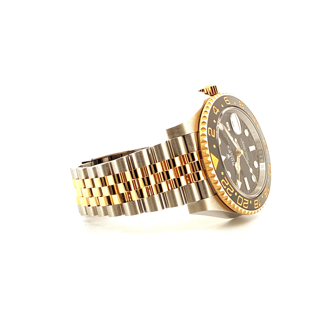 Rolex GMT-Master II Stahl Gelbgold von der Seite auf weißem Hintergrund mit goldenen und silbernen Elementen