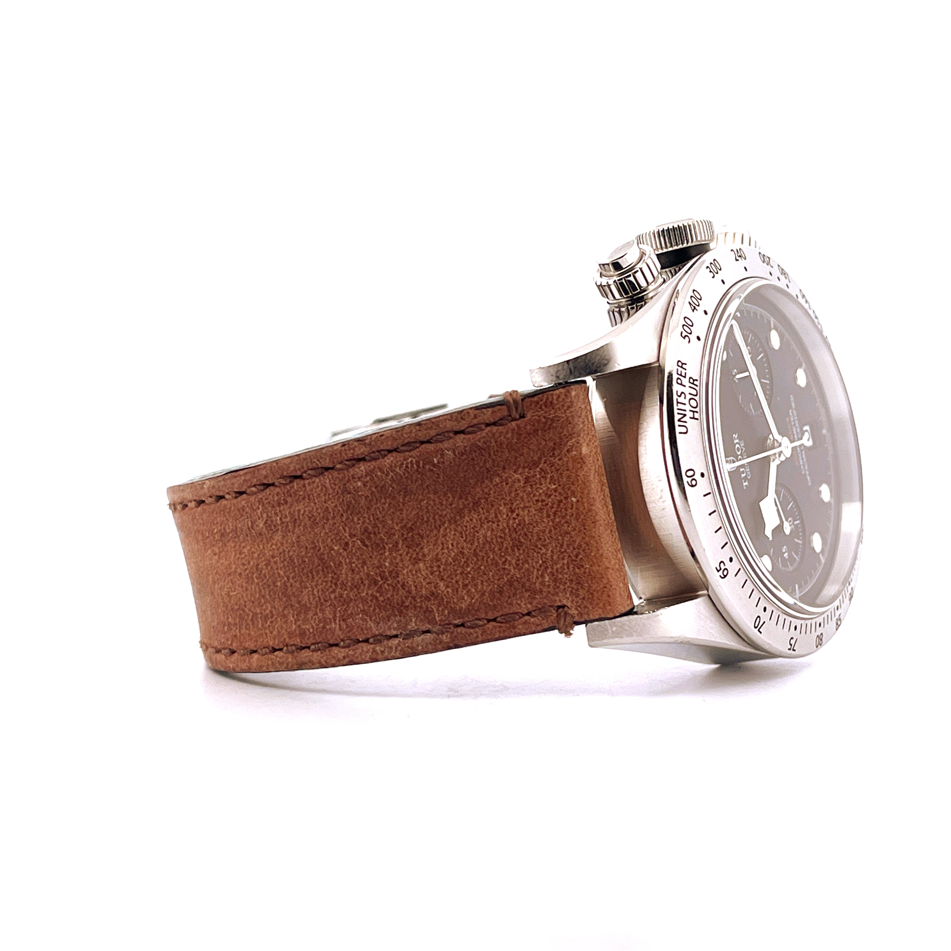 Seitliche Ansicht eines Tudor Black Bay Chrono mit braunem Lederarmband auf weißem Hintergrund