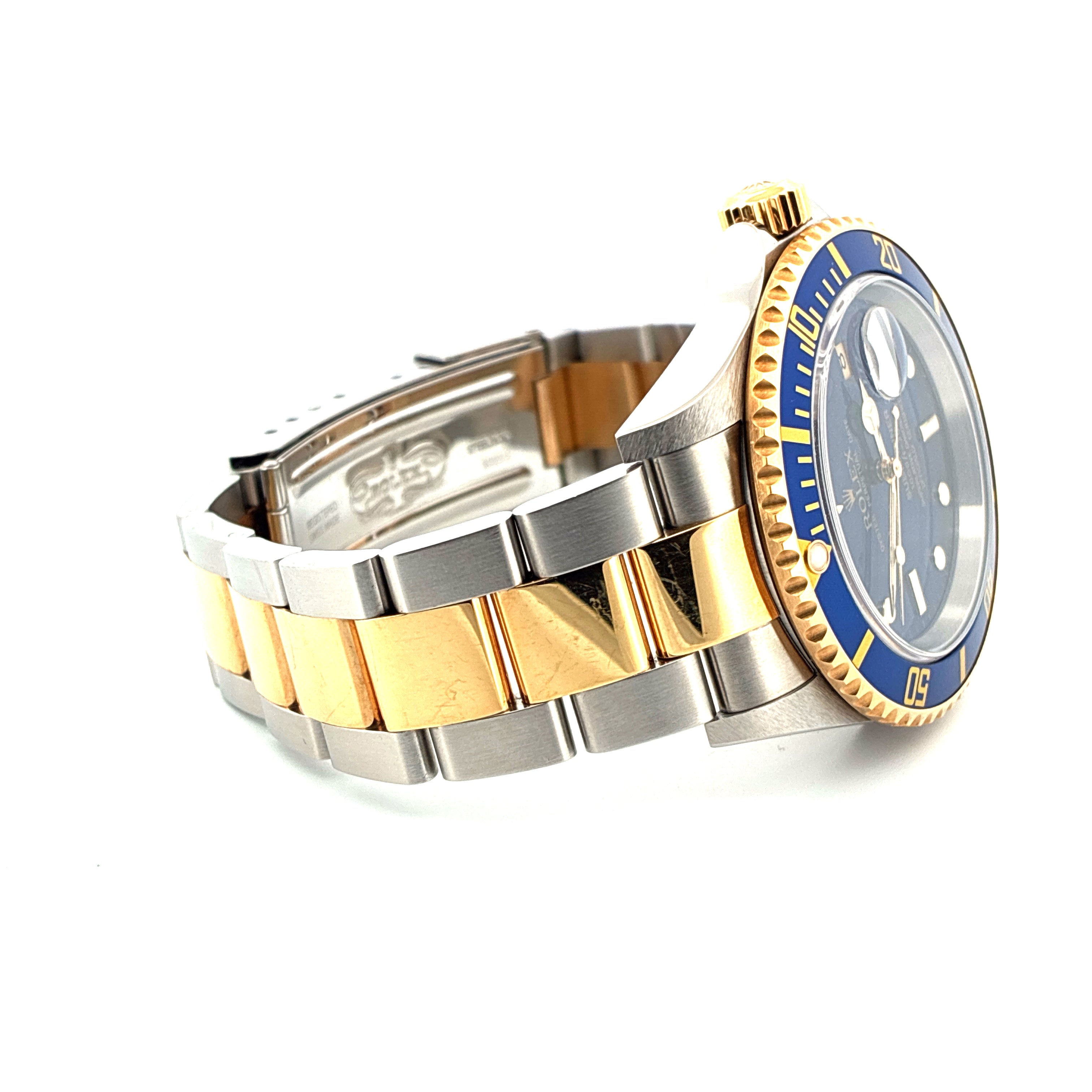Eine Rolex Submariner Date Bicolor Uhr mit blauem Zifferblatt und gold-stahlfarbenem Armband in Seitenansicht auf weissem Hintergrund